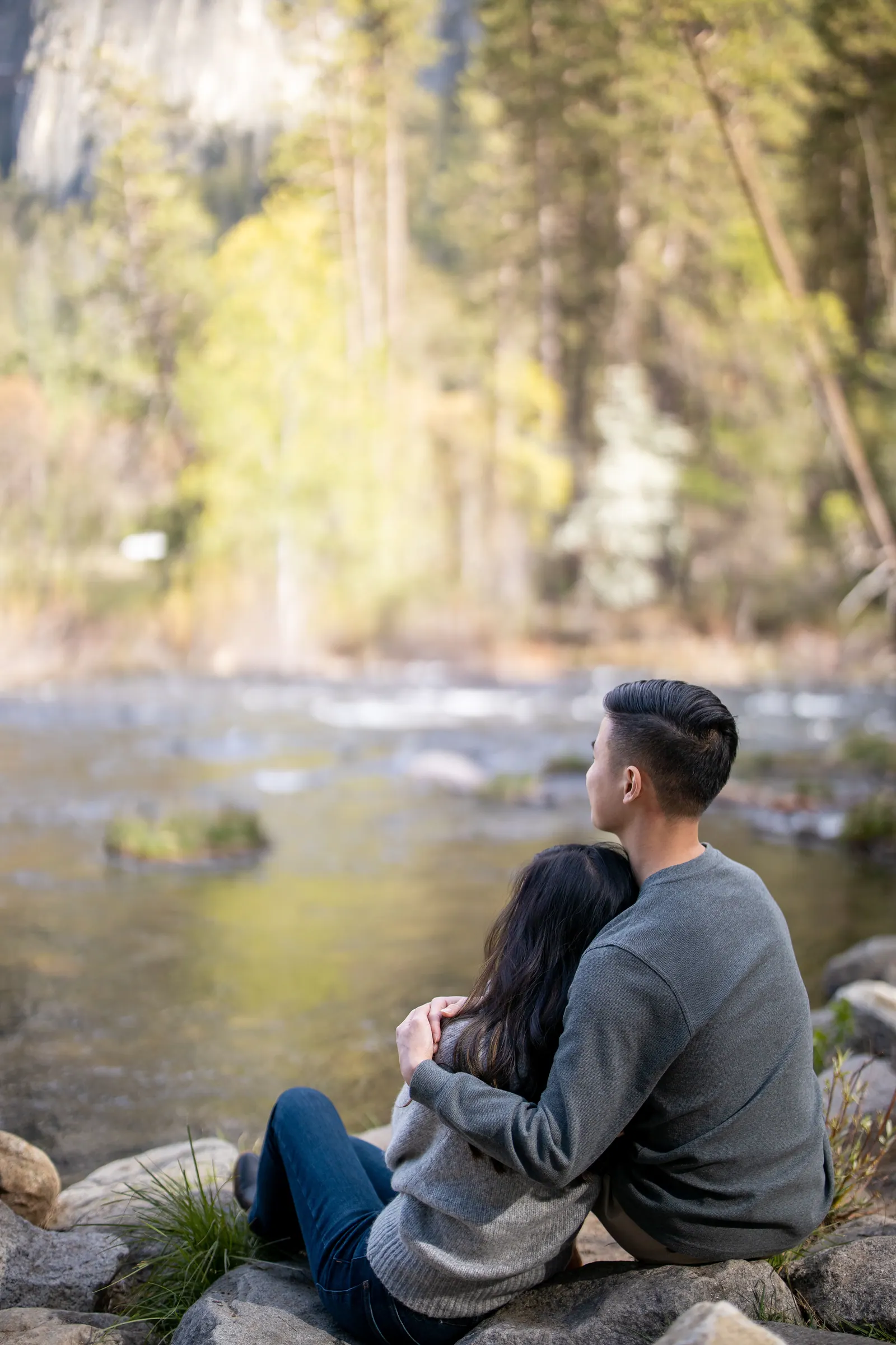 Couple sitting on rocks beside the Merced River in Yosemite