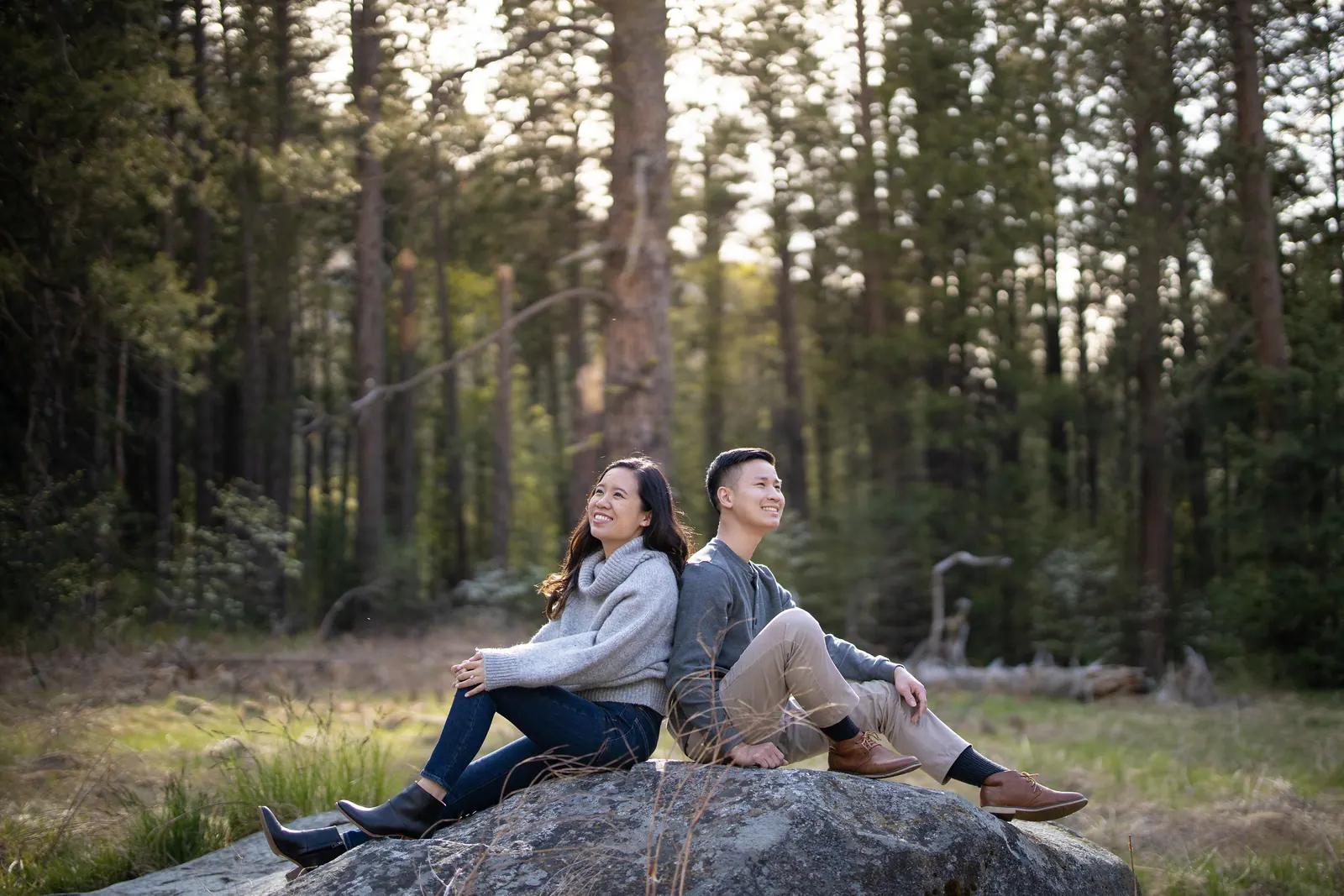 Couple lounging on a boulder in a forest clearing