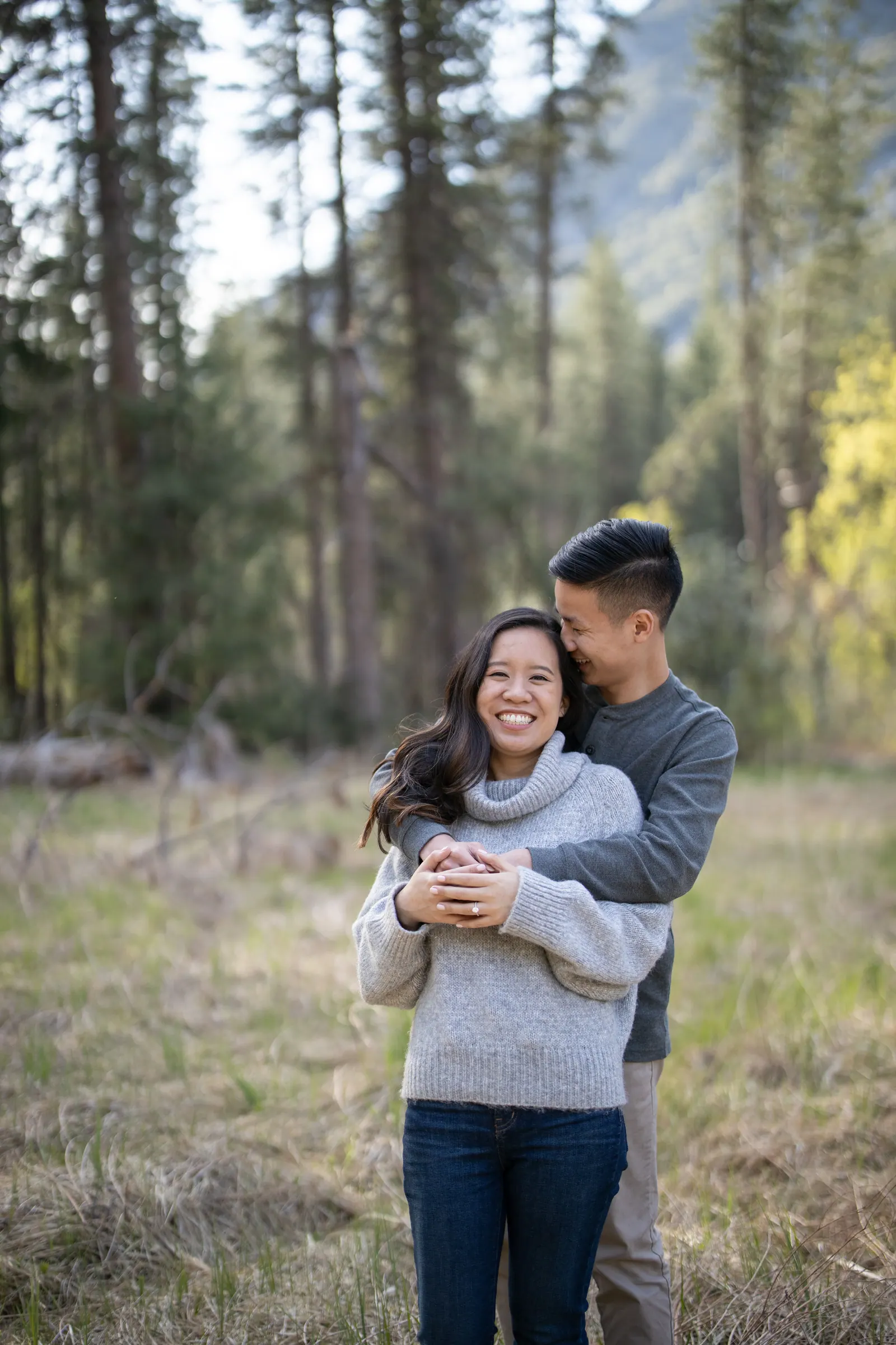 Couple hugging and laughing in a sunlit pine forest