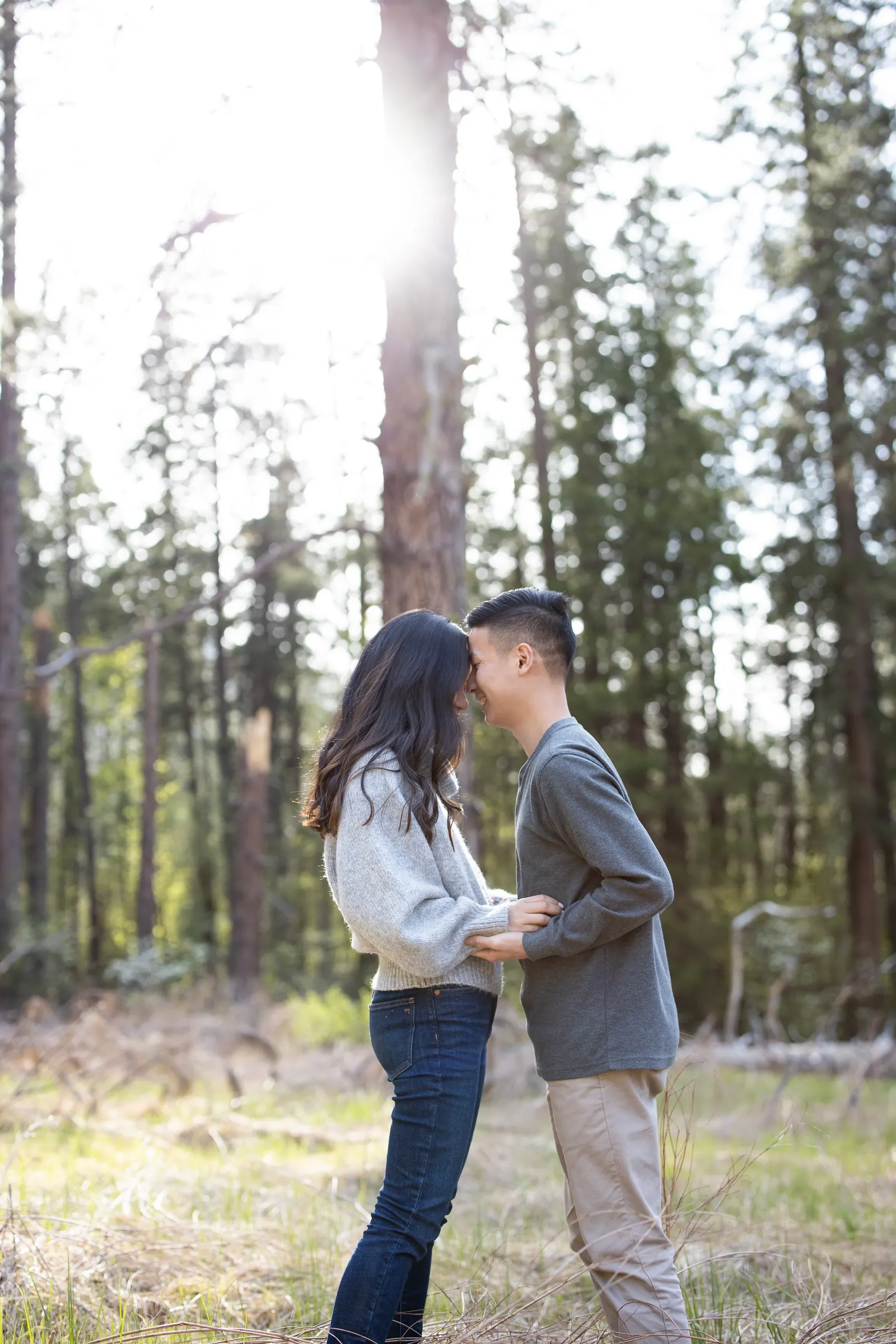 Couple holding hands among tall pines