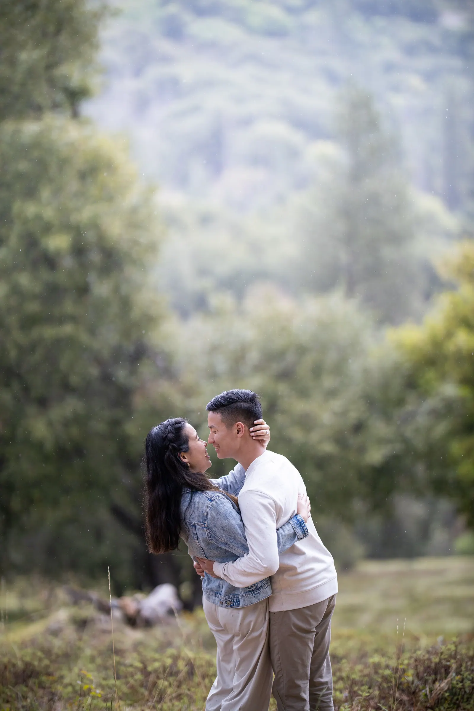 Couple embracing in a meadow with granite cliffs behind