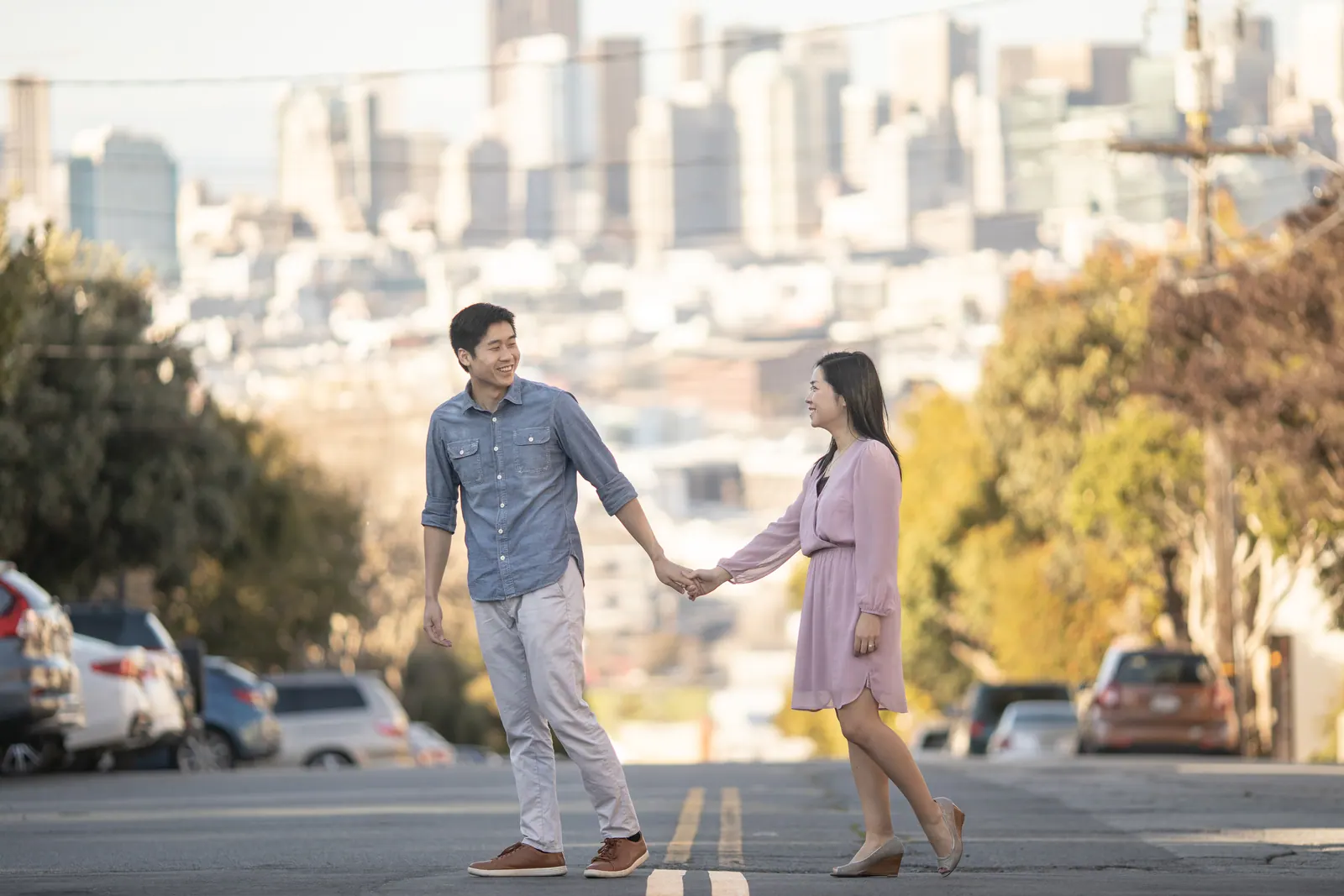 Couple holding hands on a San Francisco street with the skyline behind