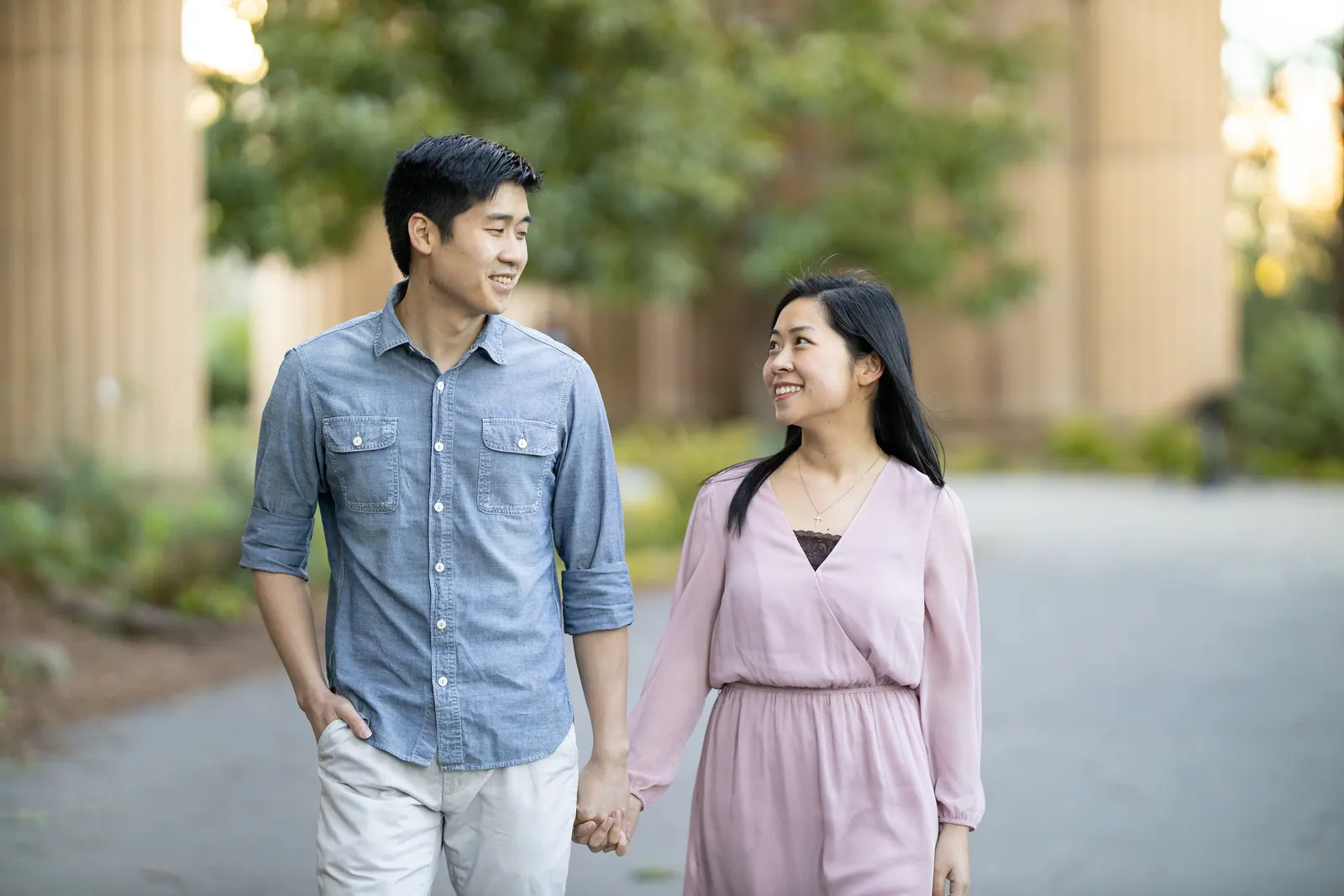 Couple walking hand in hand past classical columns
