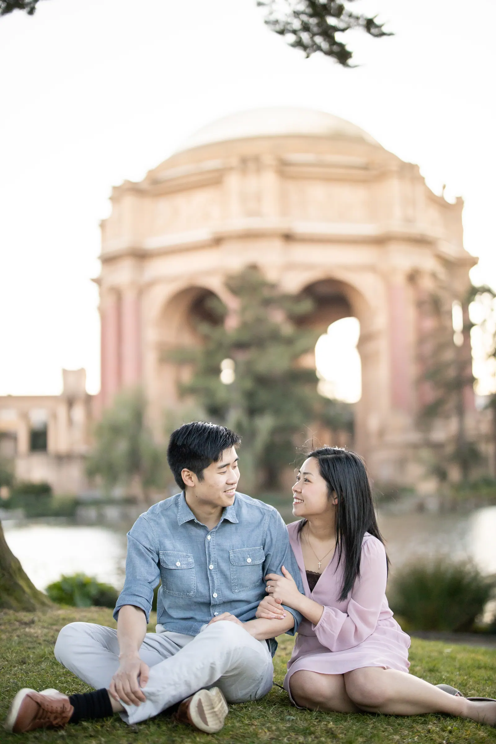 Couple sitting on the lawn in front of the Palace of Fine Arts rotunda