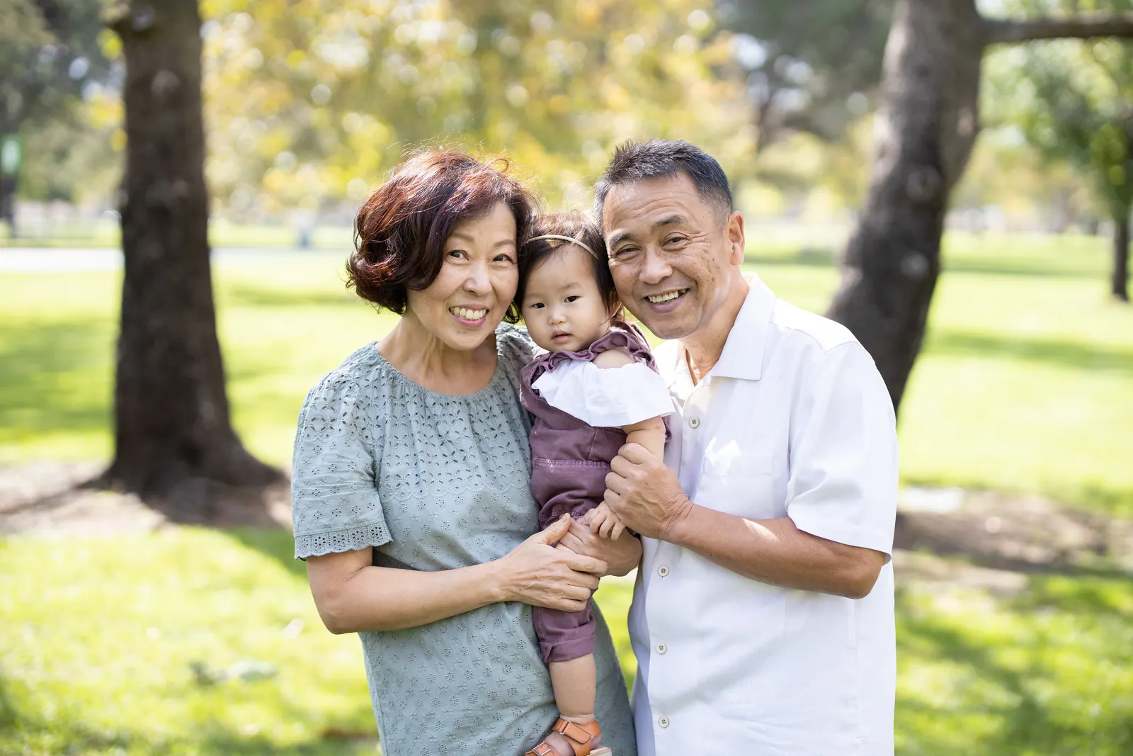 Grandparents holding their granddaughter in a park