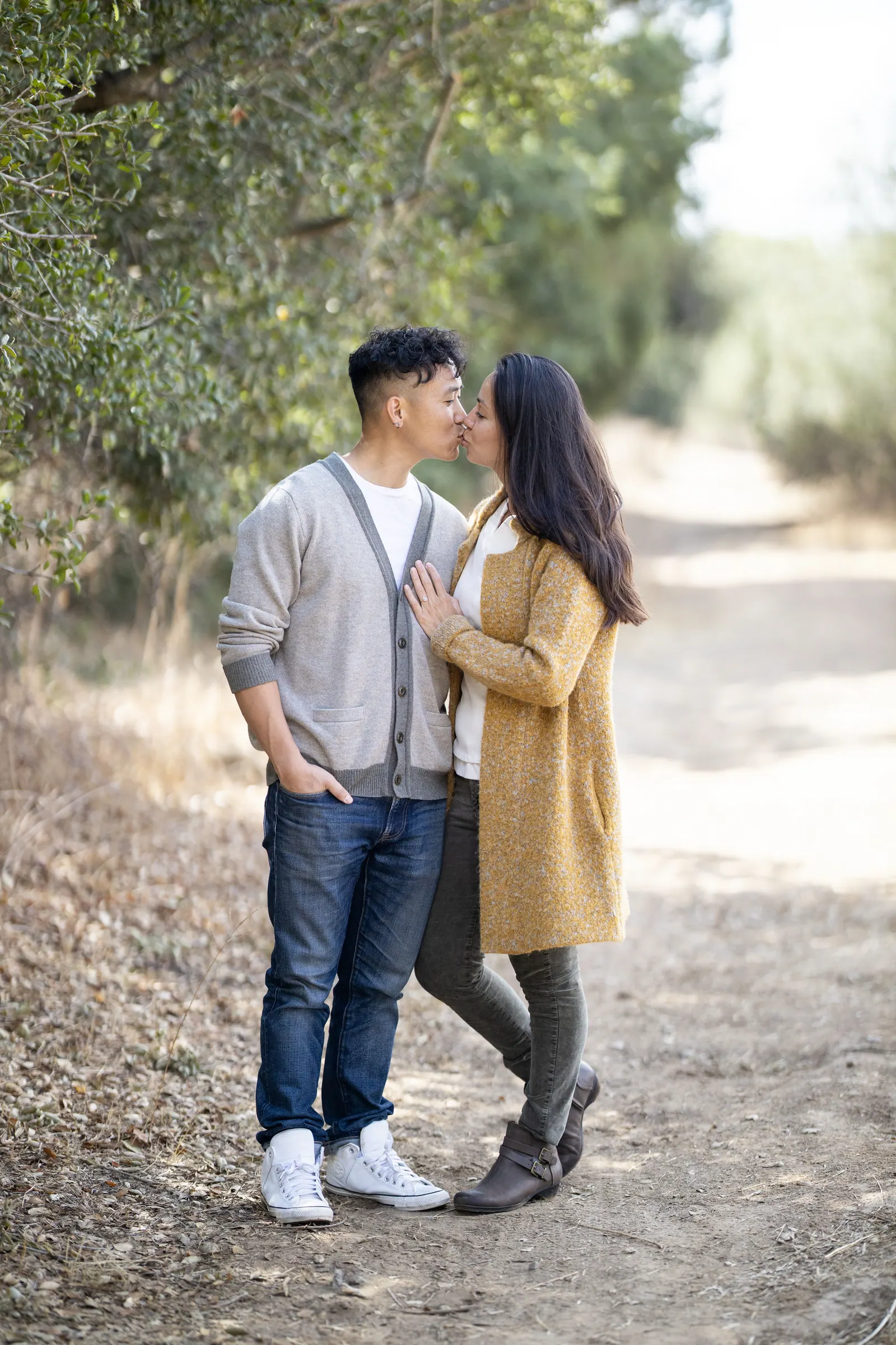 Couple embracing on a dirt path under trees