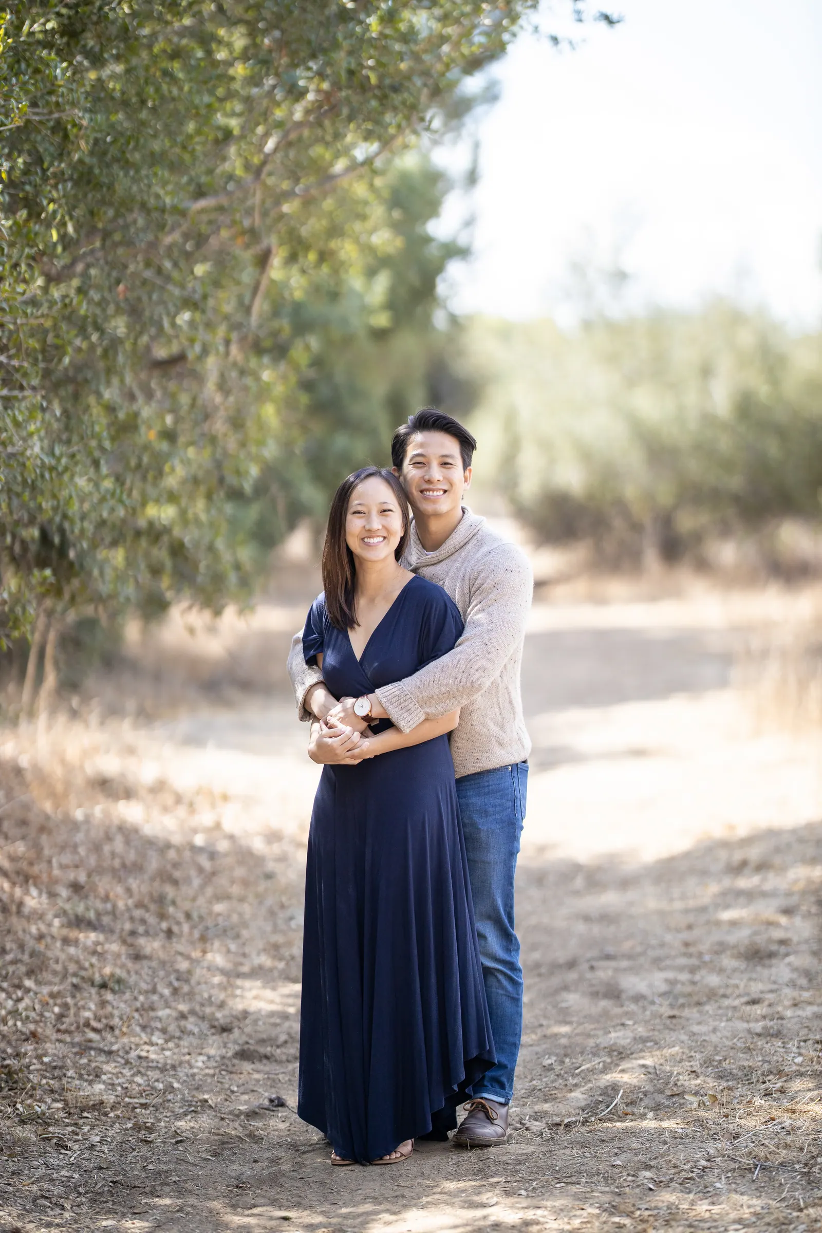 Expecting couple standing on a tree-lined path