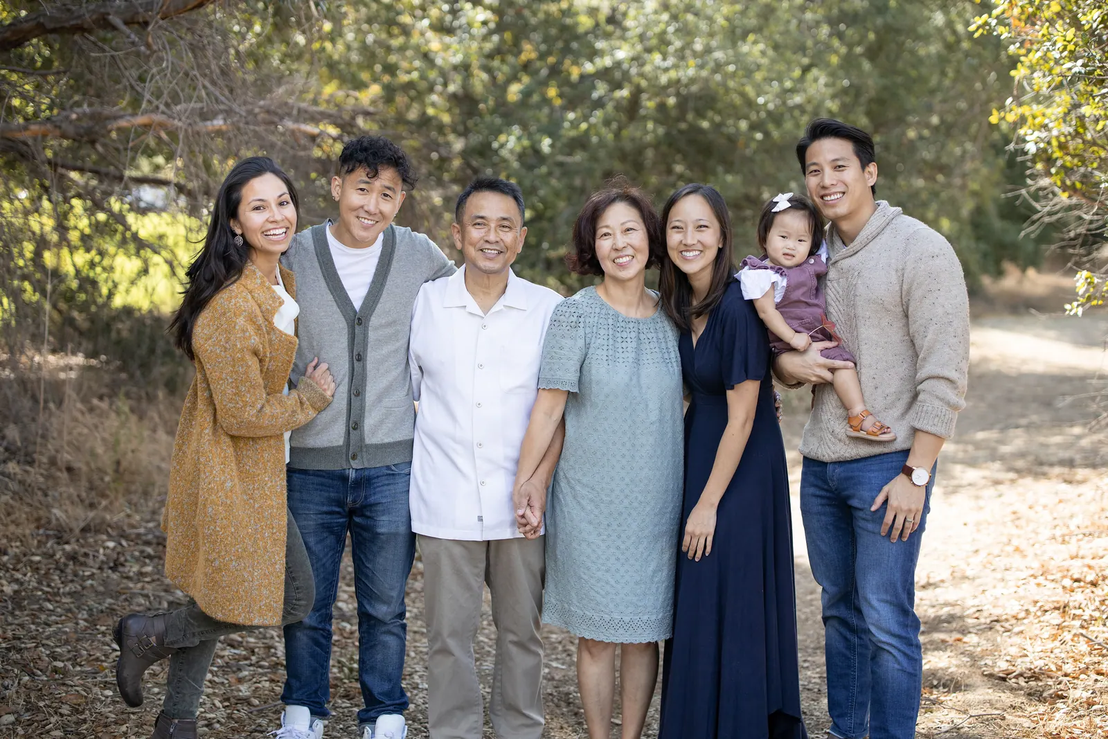 Multi-generational family group portrait under trees