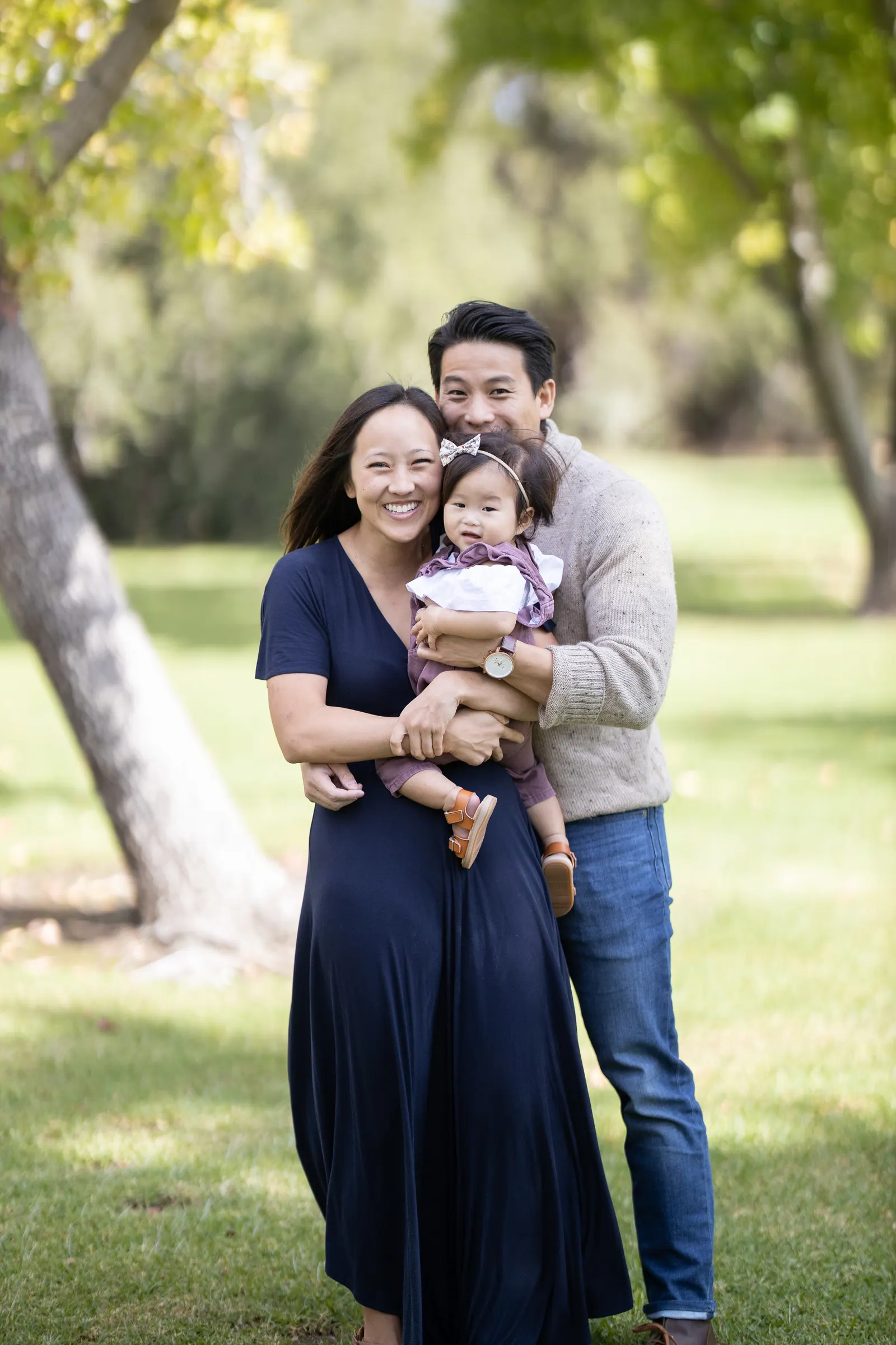Parents holding their toddler in a sunny park