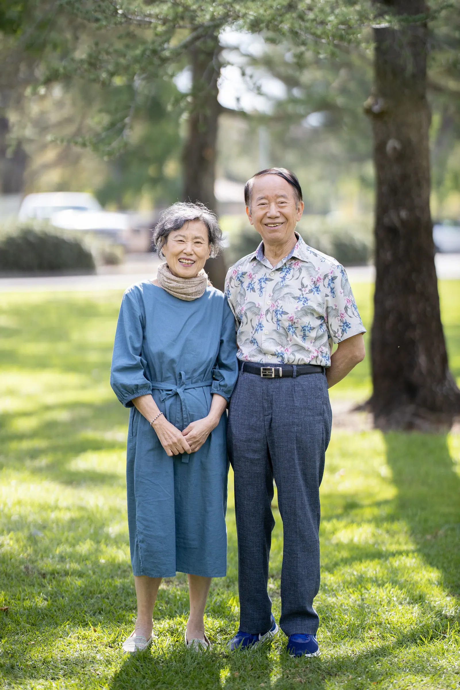 Older couple standing together on a lawn under trees