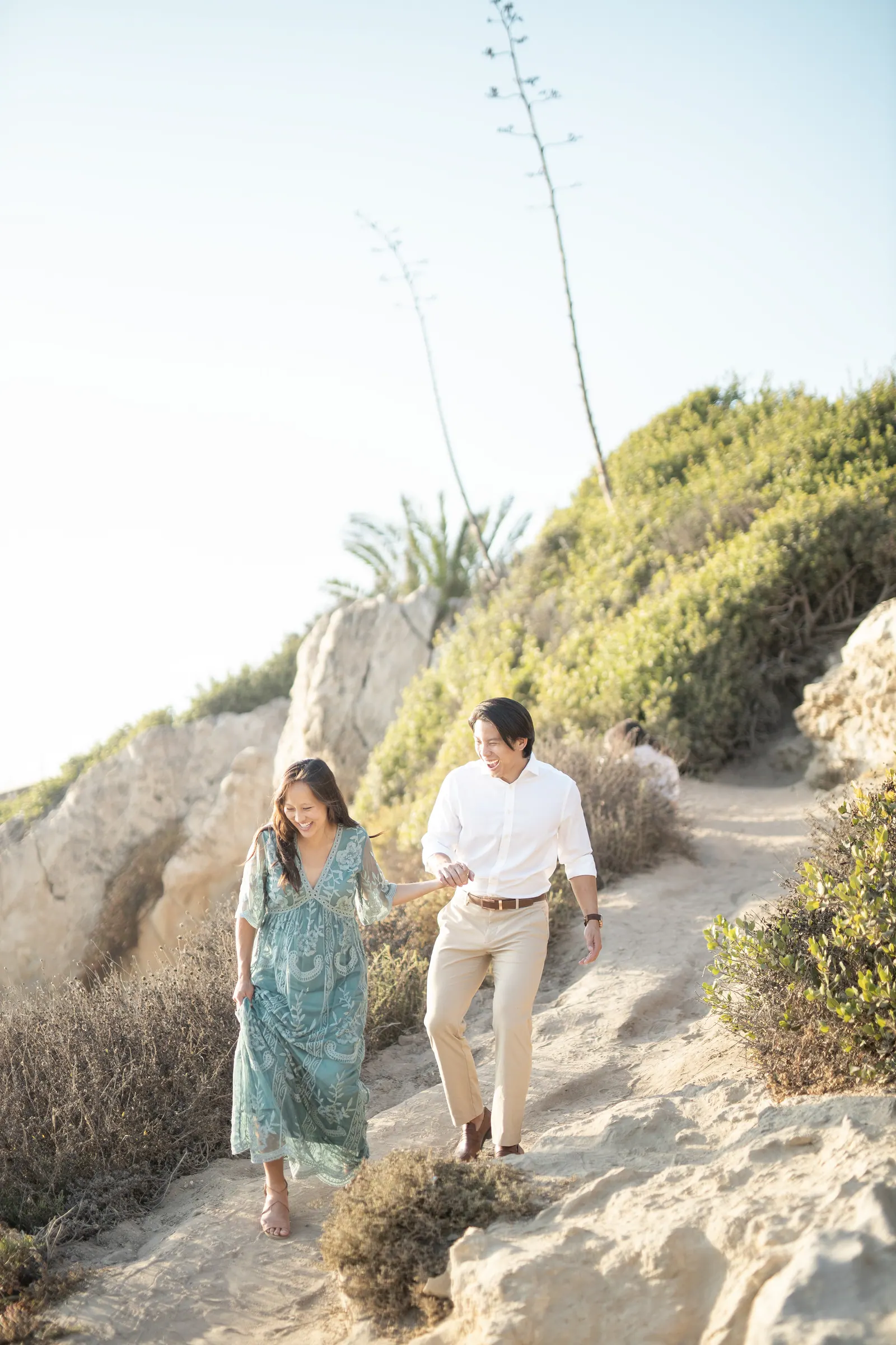 Couple walking down a coastal trail toward the ocean