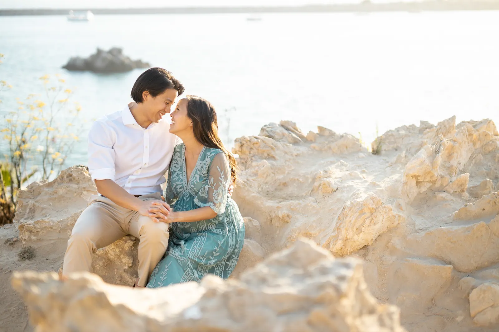 Couple sitting together on sandstone rocks by the sea