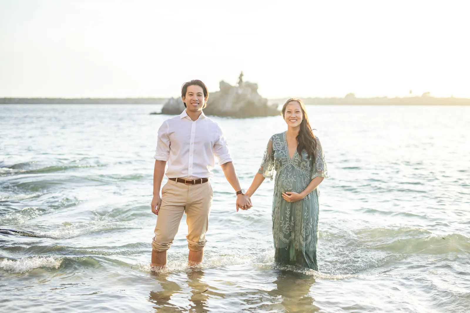 Couple holding hands while wading in the ocean