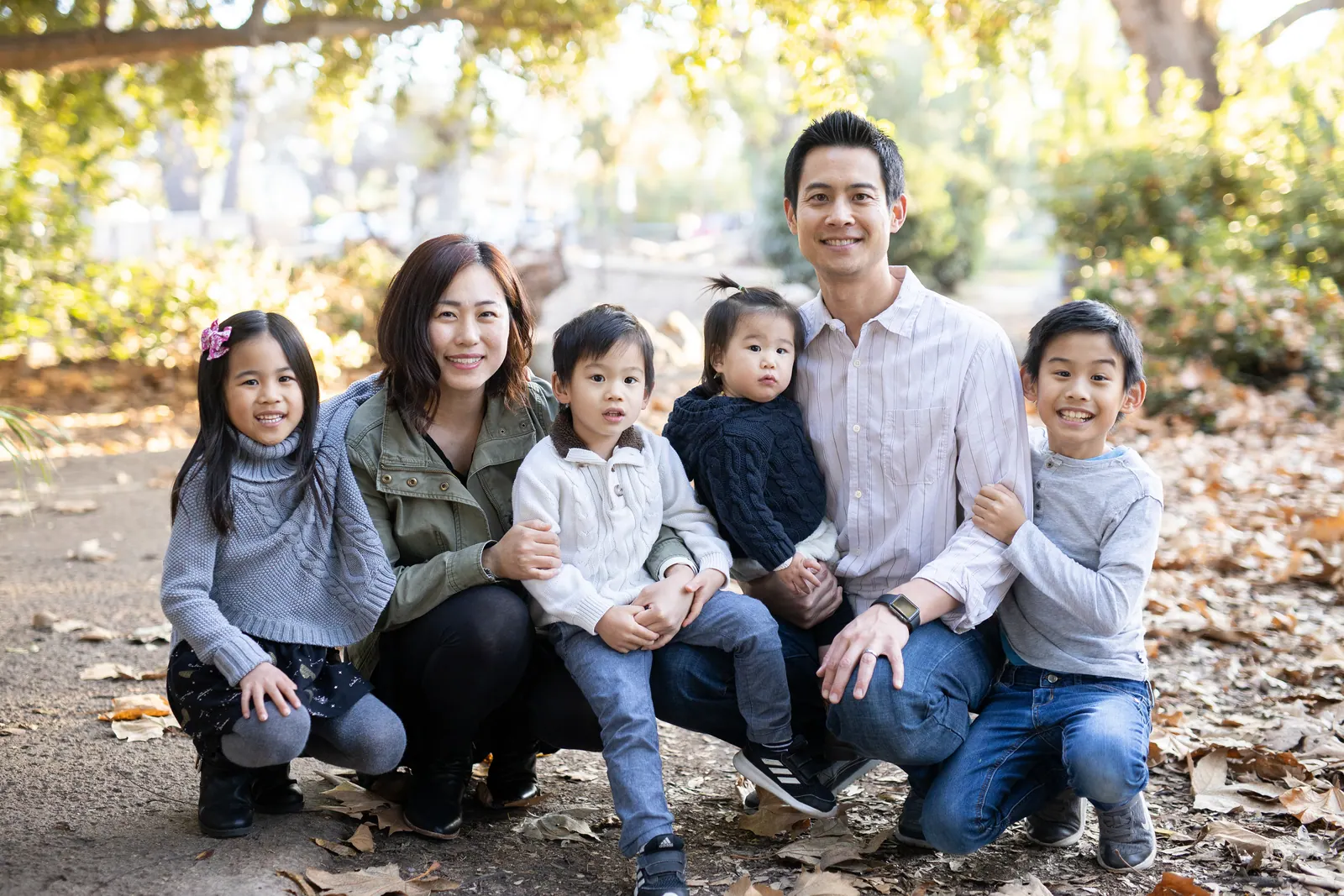 Family of six sitting together under trees