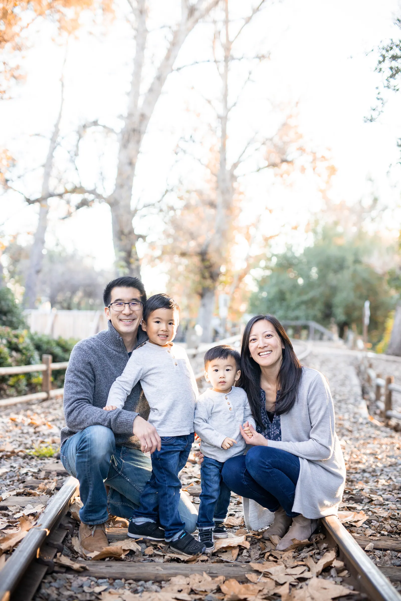 Family sitting on old railroad tracks in the woods