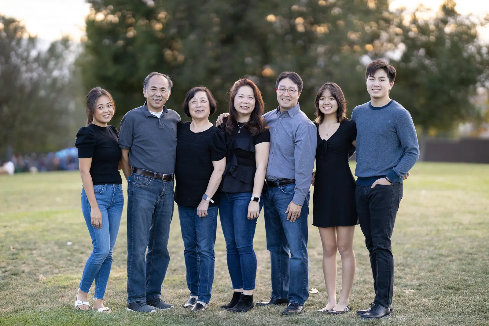 Adult siblings and parents standing on a park lawn