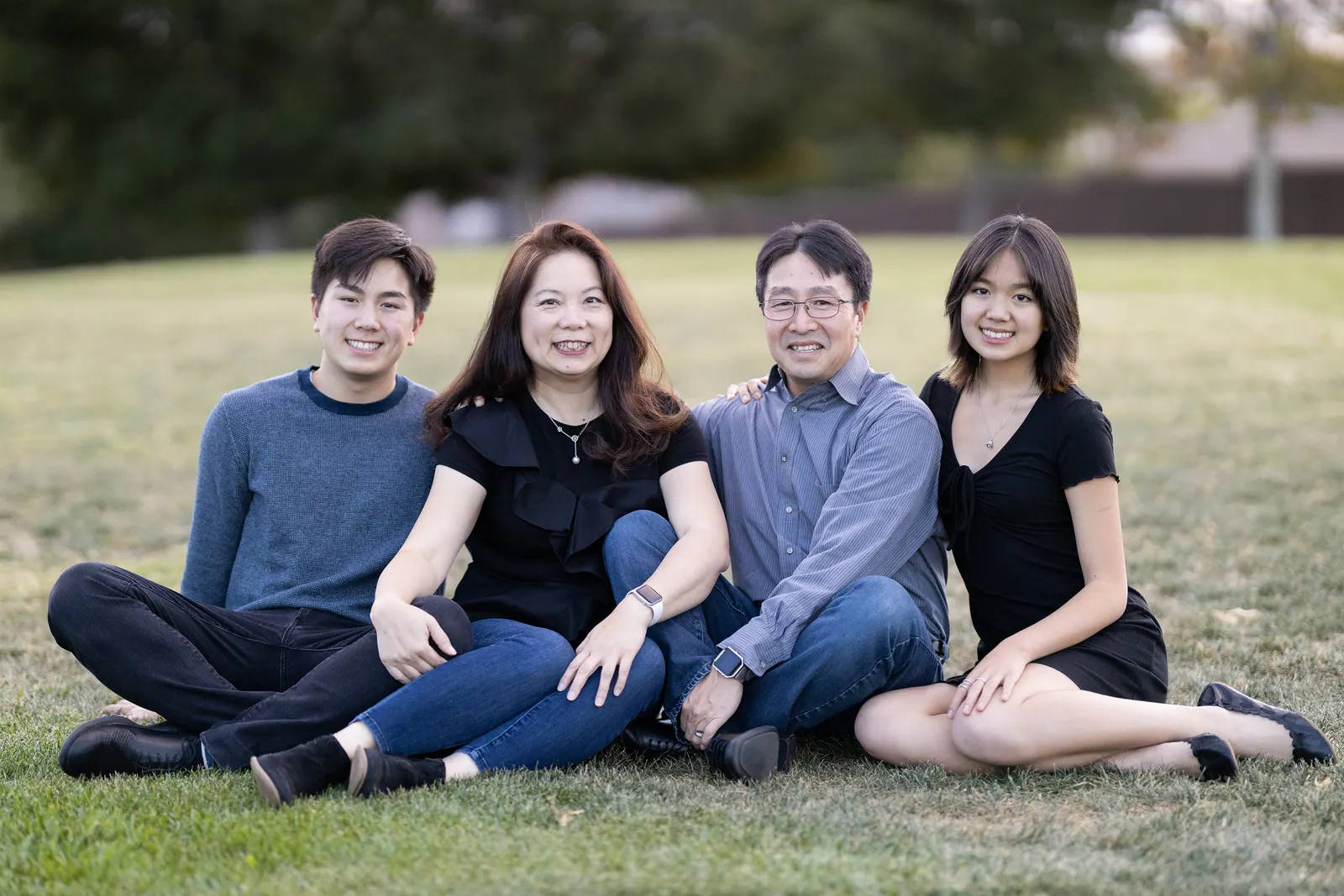 Family of four sitting on the grass laughing