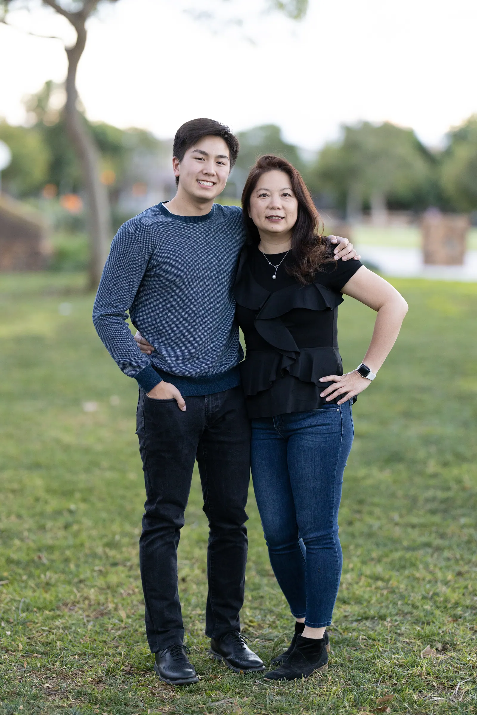 Couple standing side by side on a lawn at dusk