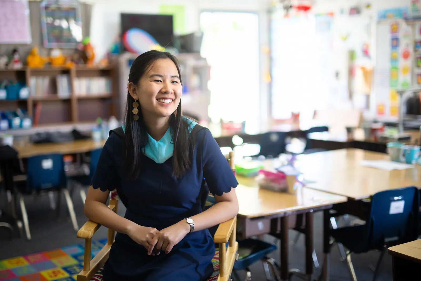 Graduate smiling at a desk in a classroom