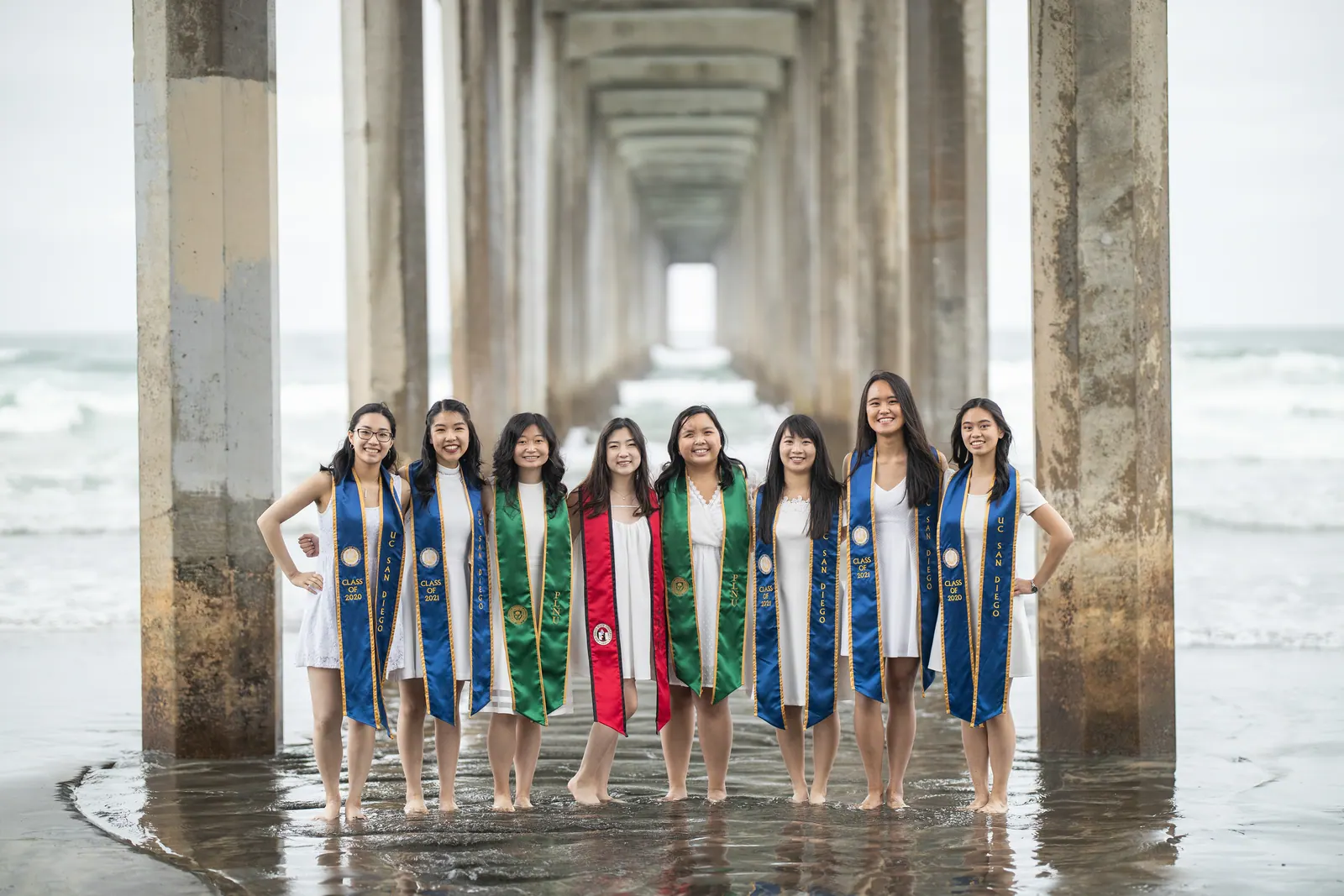 Group of graduates with stoles beneath a concrete pier