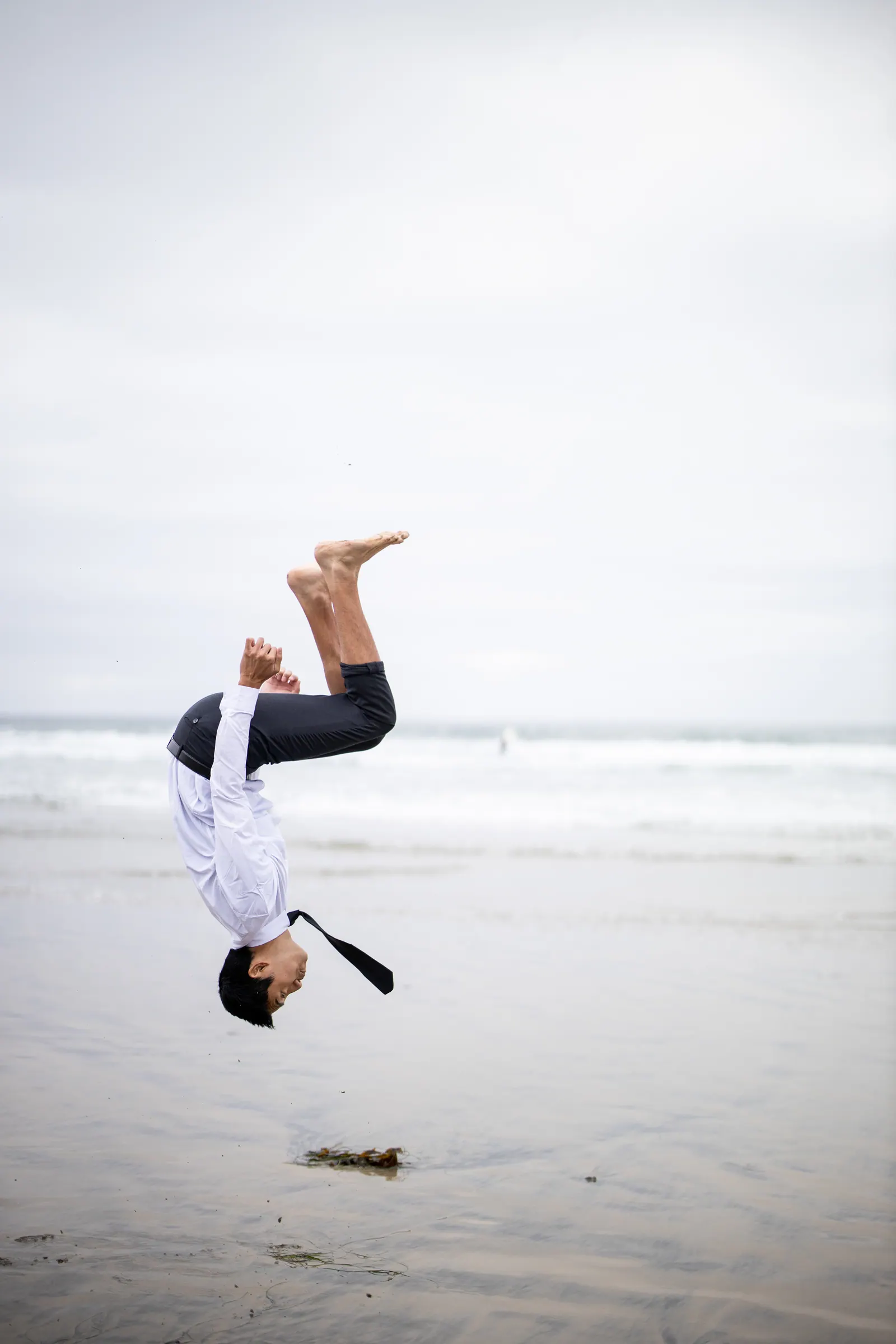 Graduate doing a handstand flip on the beach
