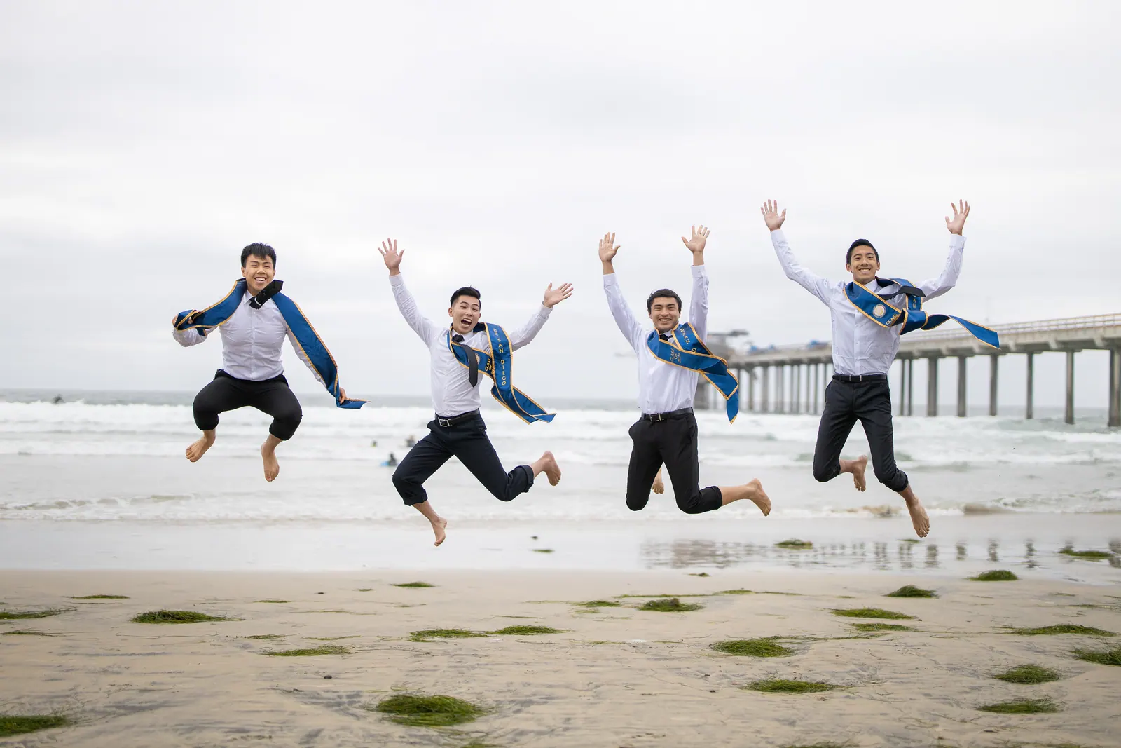 Graduates jumping in the air on the beach