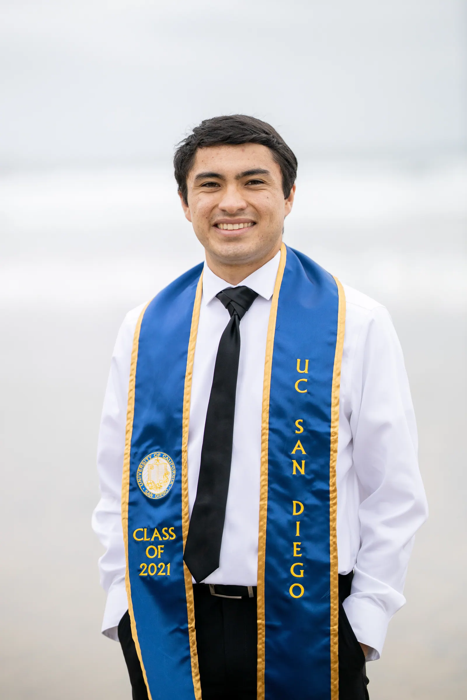 UC San Diego graduate in a suit and blue stole