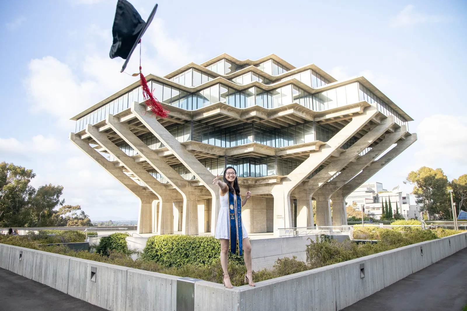 Graduate tossing a cap in front of Geisel Library