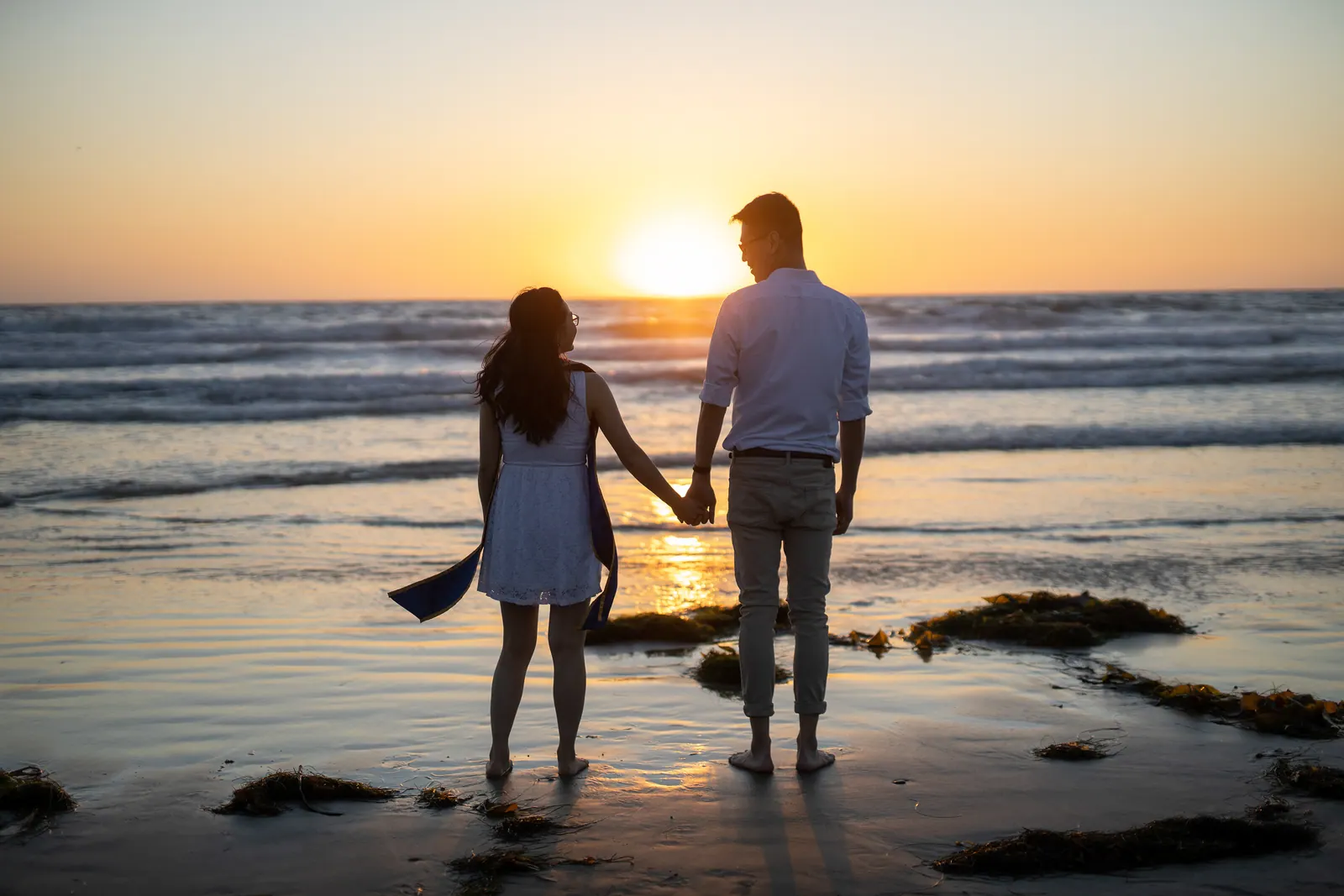 Couple holding hands on the beach at sunset