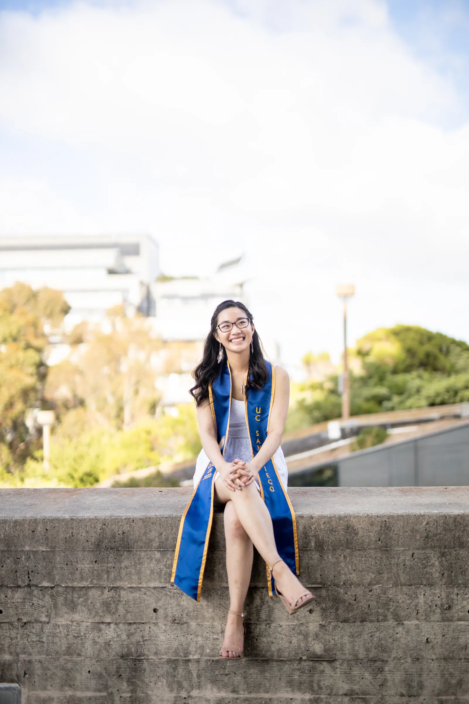 Graduate sitting on a concrete wall with a stole