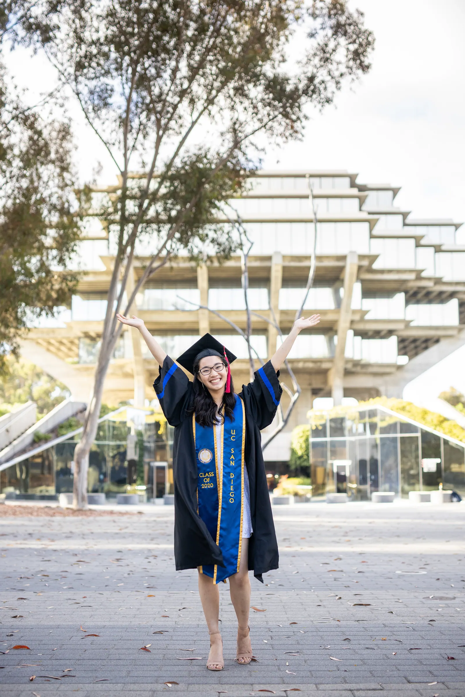 Graduate in a gown in front of Geisel Library