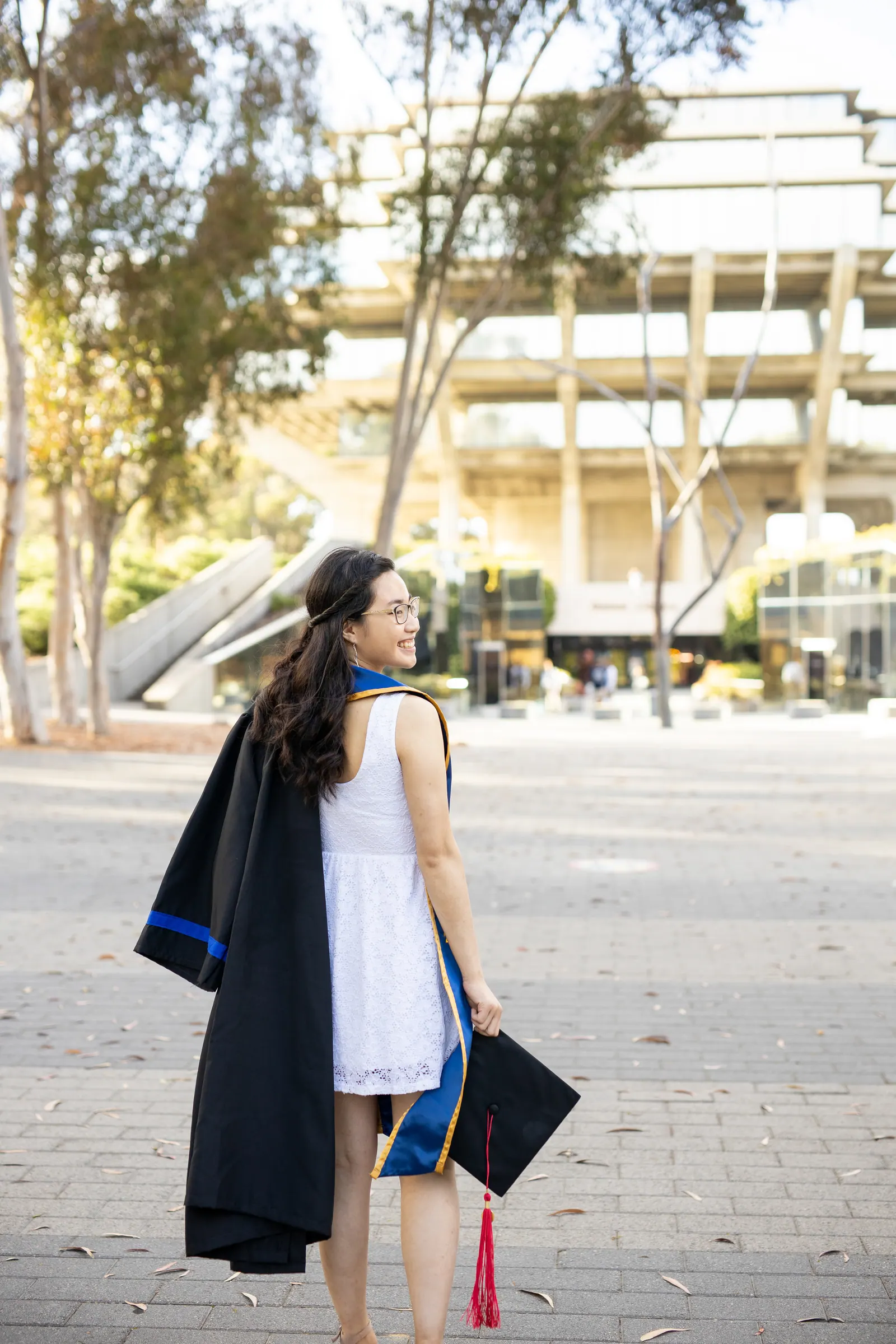 Graduate holding her gown over her shoulder on campus