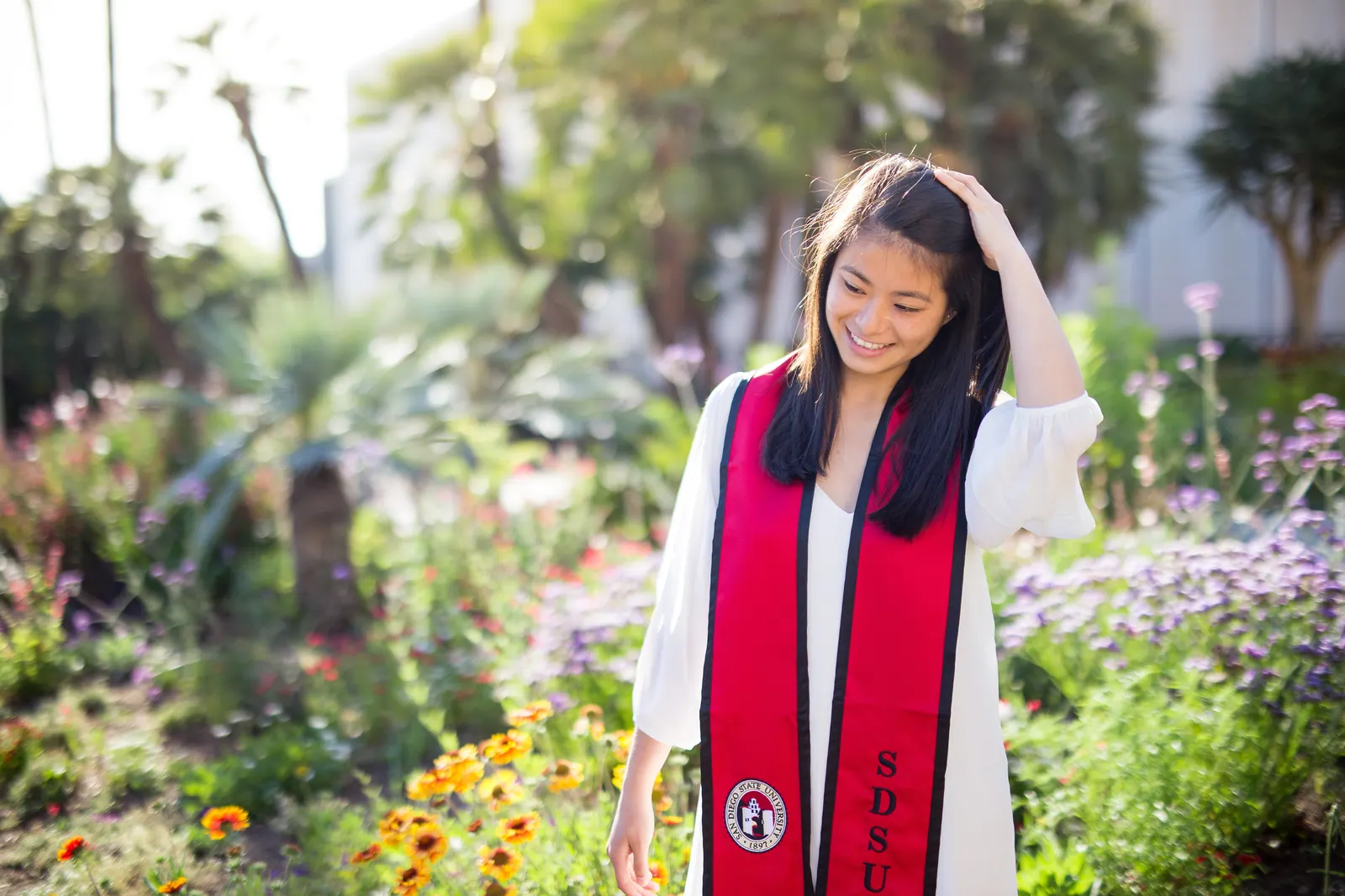 Graduate in a red stole among garden flowers