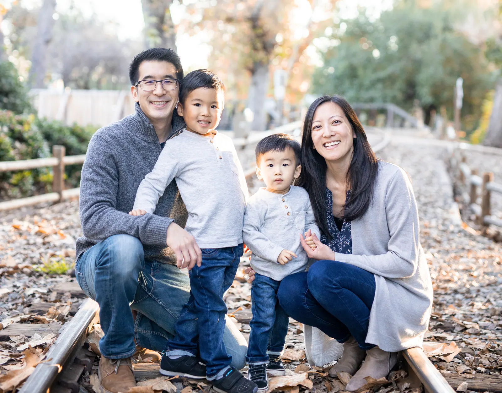 Family of four with two young boys sitting together outdoors