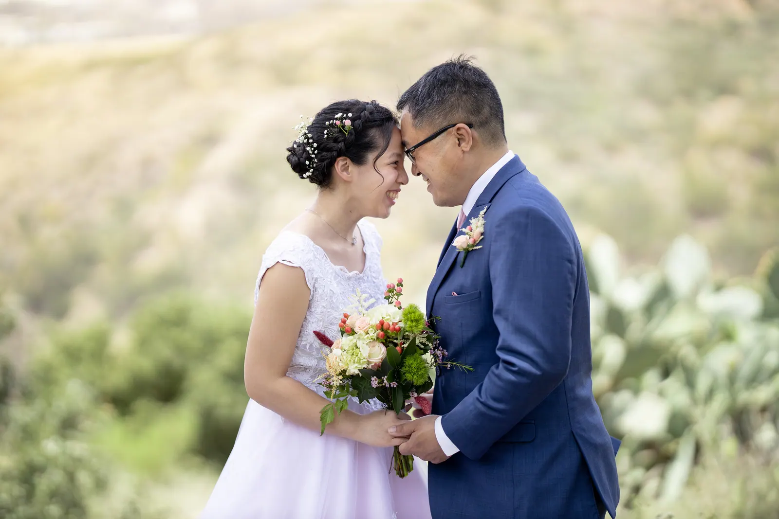 Bride holding her bouquet beside the groom in a navy suit, outdoor portrait
