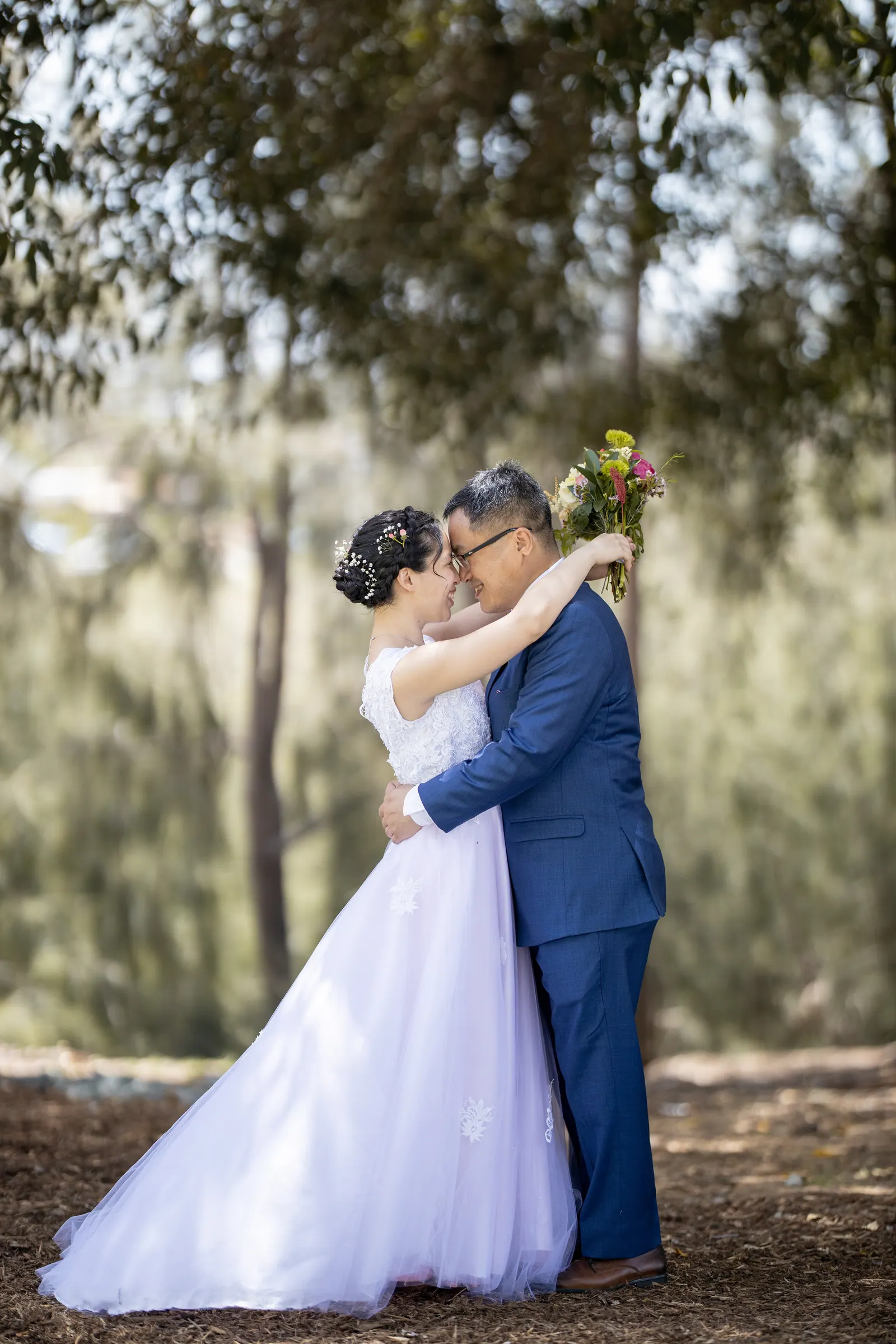 Groom kissing the bride under oak trees