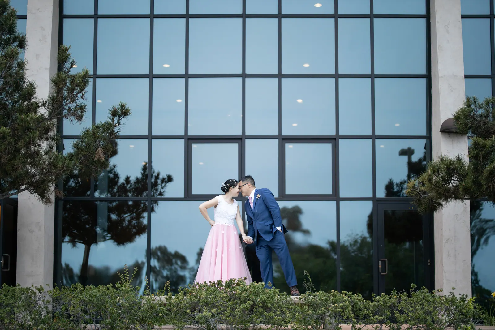Bride and groom in front of a modern glass building
