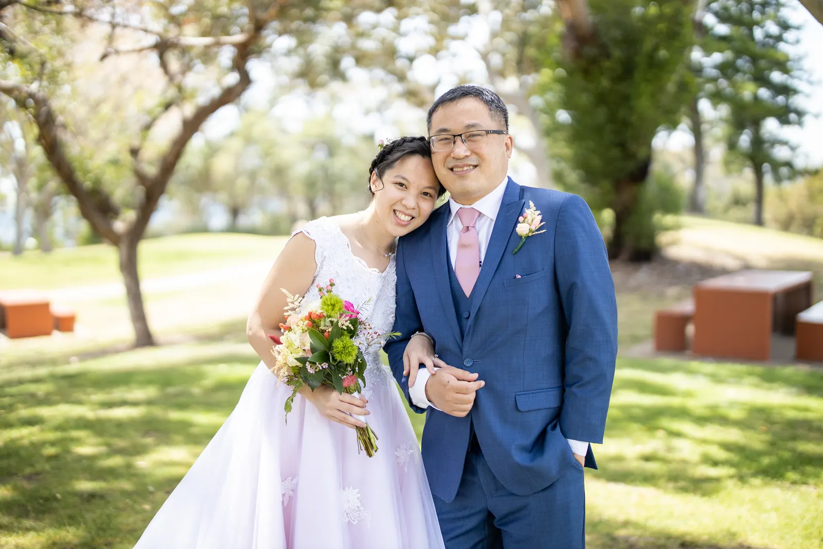 Bride leaning against the groom, smiling outdoors