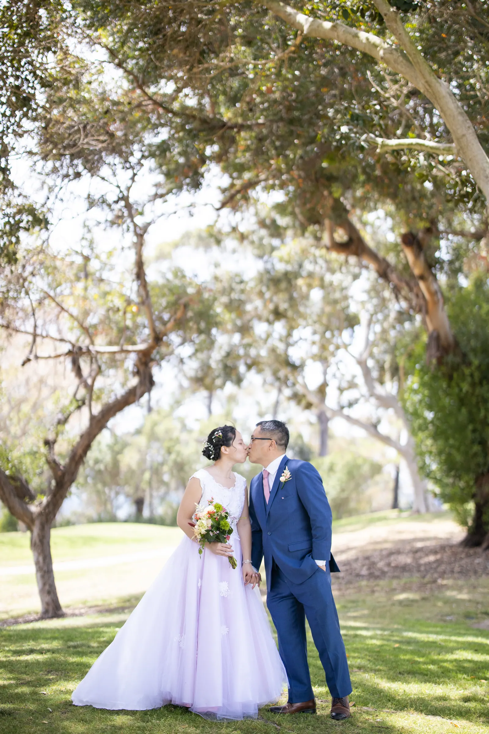 Bride and groom kissing under a large oak tree