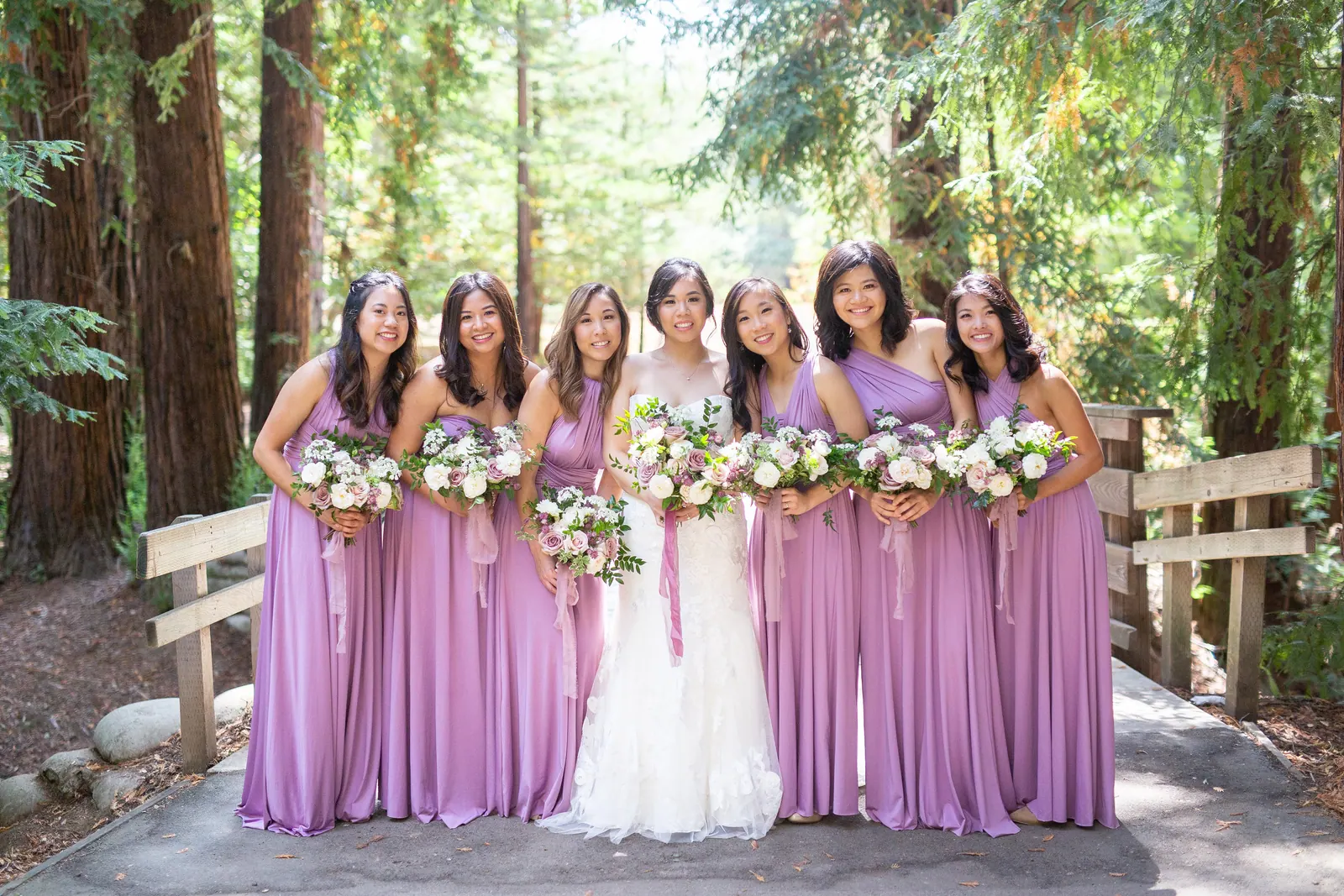 Bride with bridesmaids in lavender dresses on a forest boardwalk