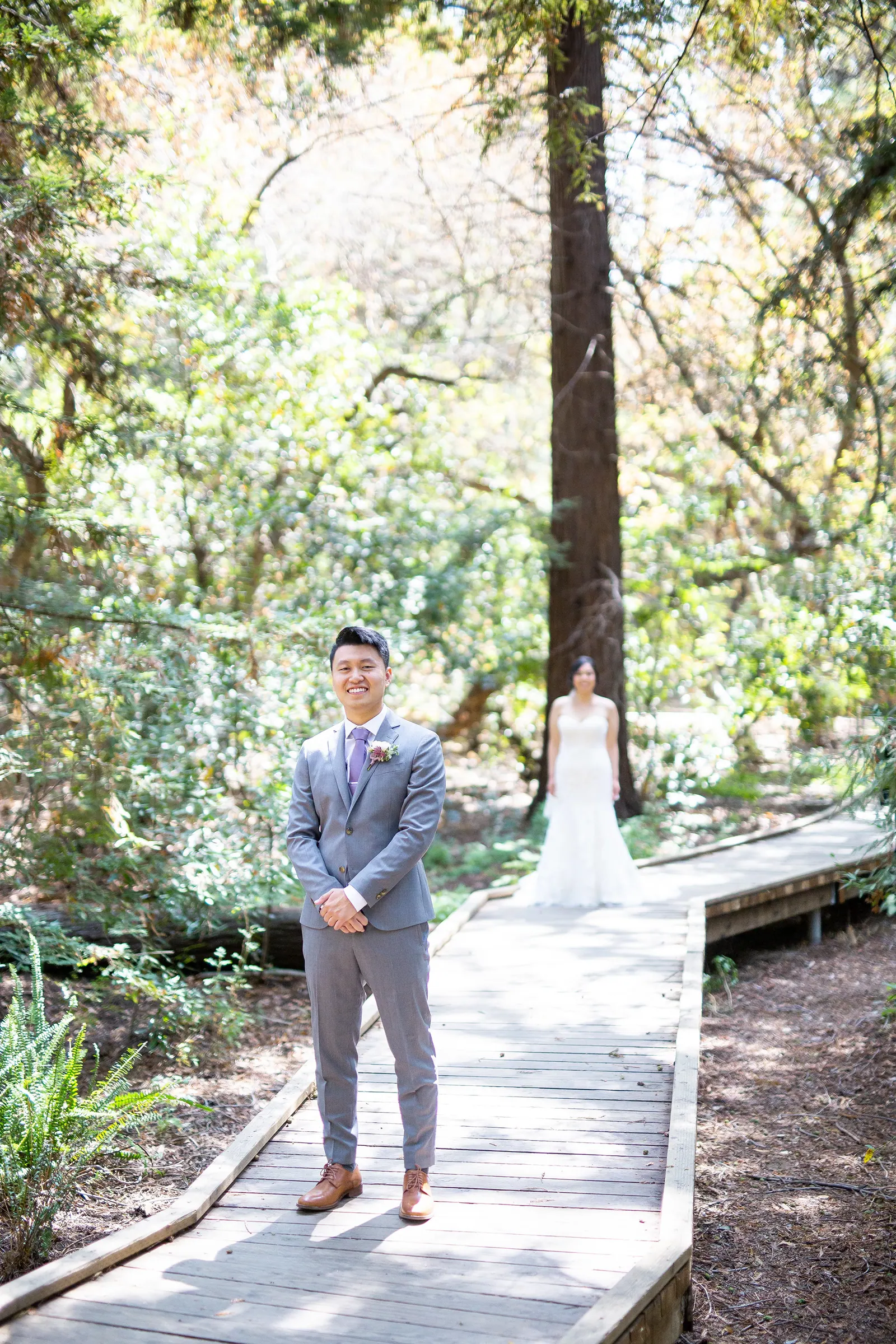 Couple walking along a wooden boardwalk through tall redwoods