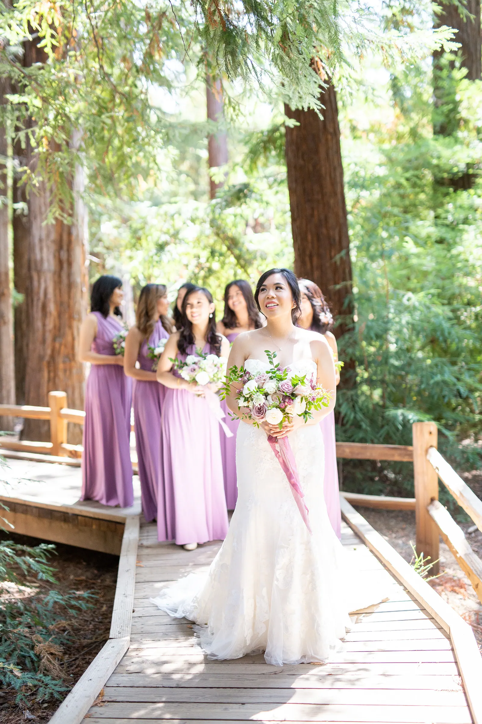 Bride surrounded by bridesmaids in lavender dresses in the forest