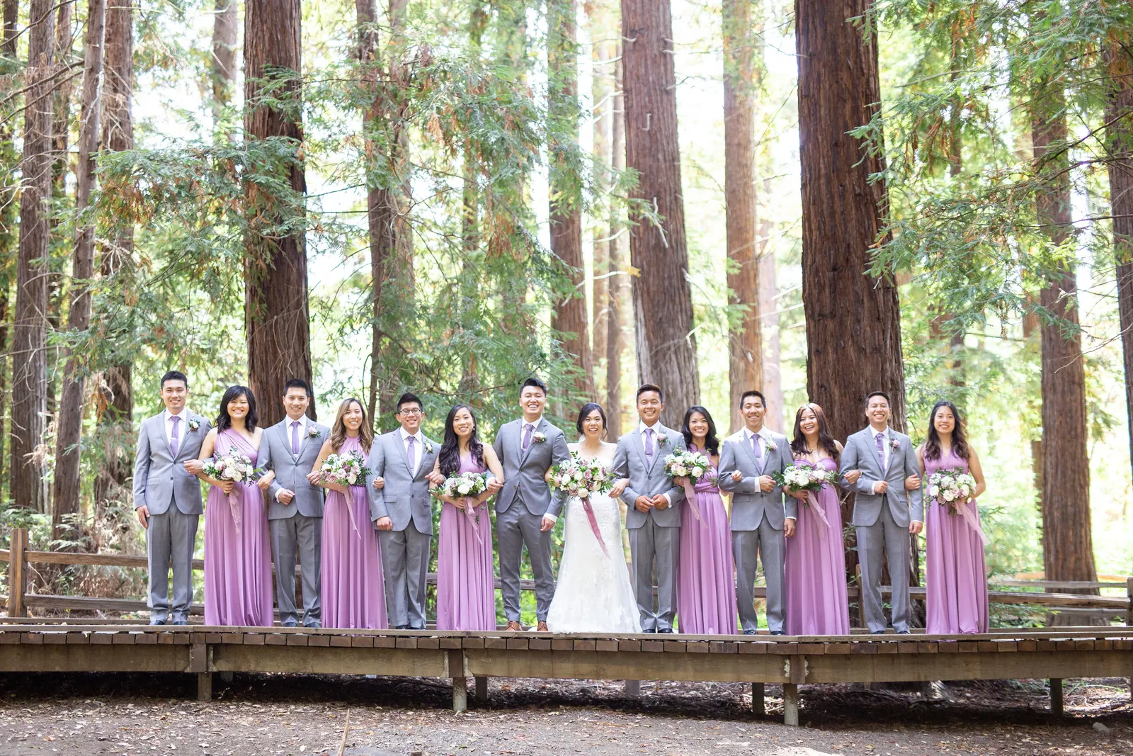 Wide shot of the bridal party on a boardwalk beneath redwoods