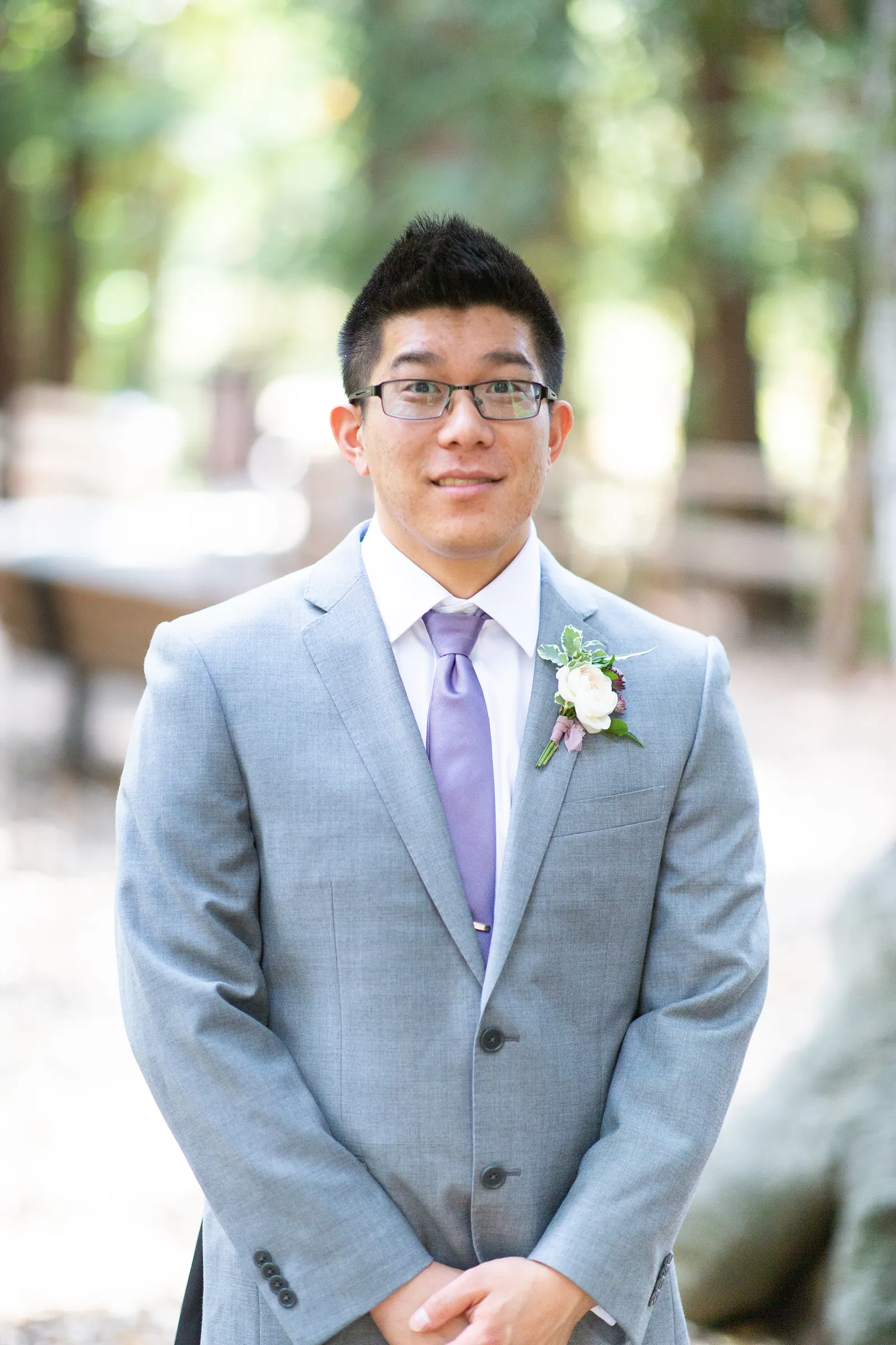 Groomsman in a grey suit and glasses portrait in the forest