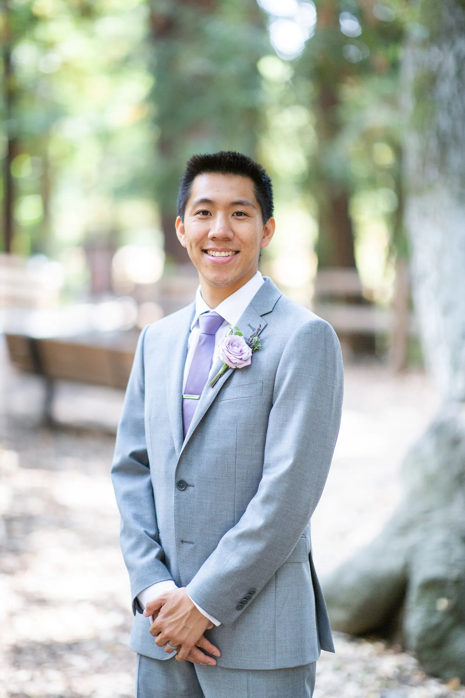 Groomsman in a grey suit standing on a forest path