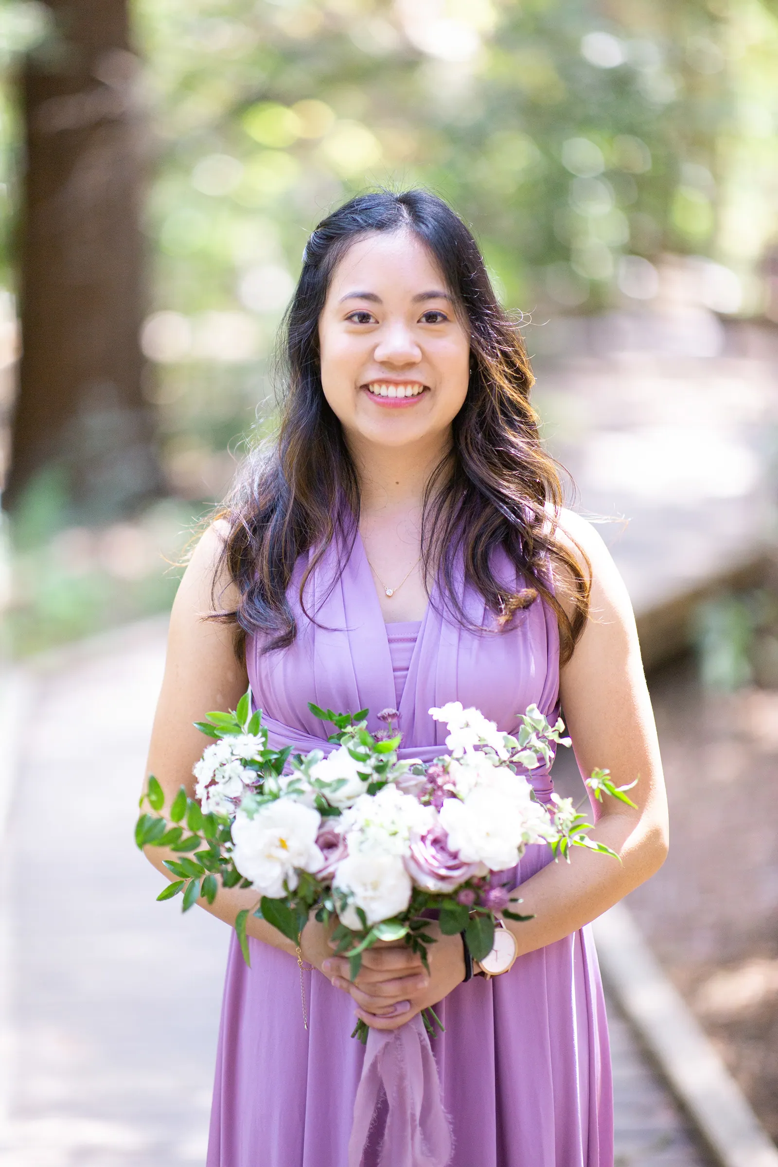 Bridesmaid with long hair in a lavender dress holding flowers