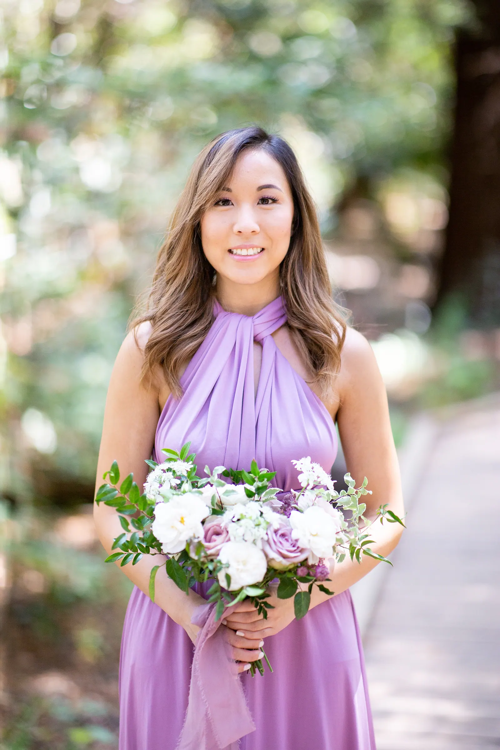 Bridesmaid in lavender smiling with a bouquet