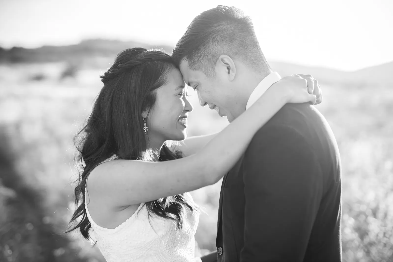 Black and white portrait of the couple touching foreheads in a meadow