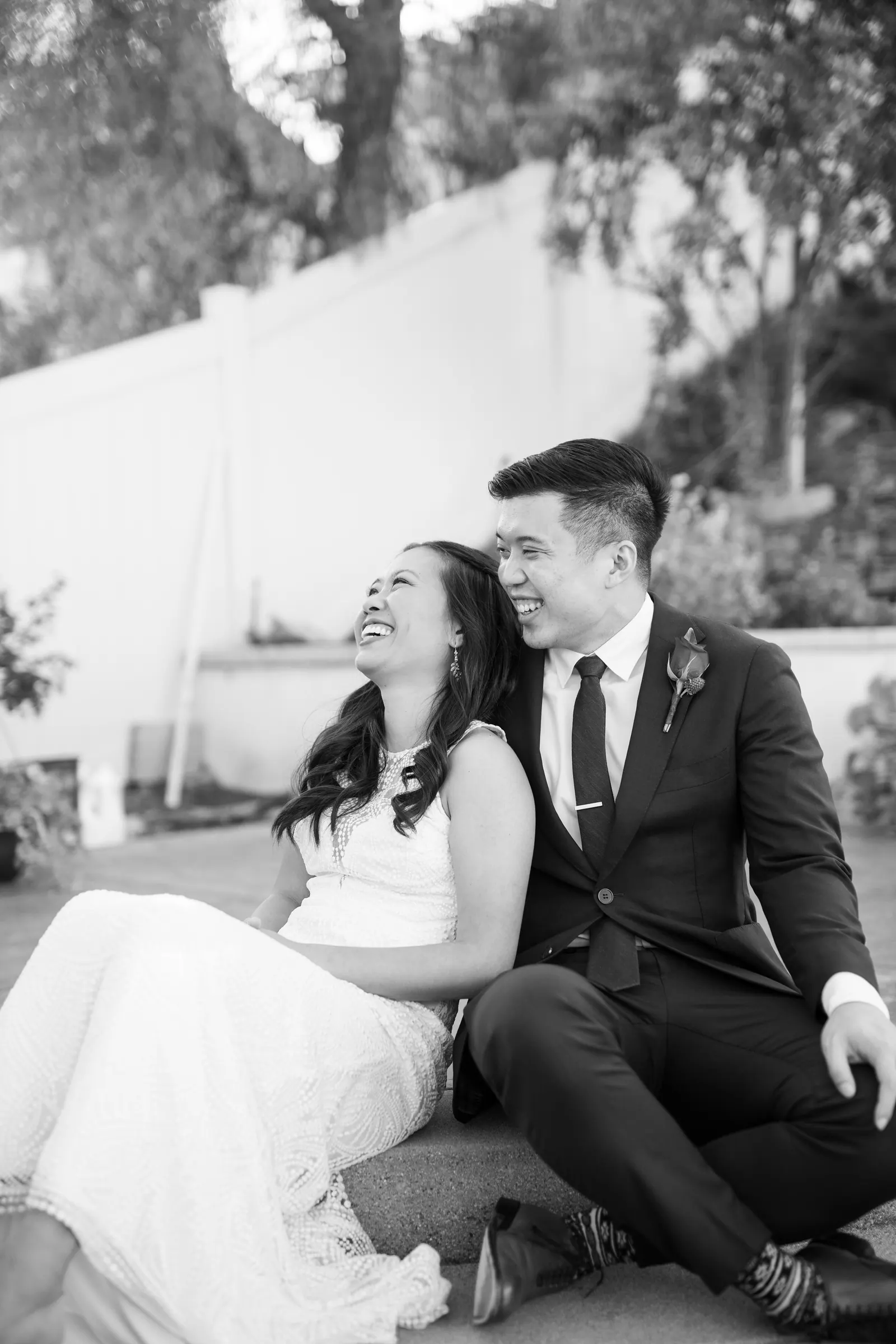 Black and white photo of bride and groom sitting together outdoors