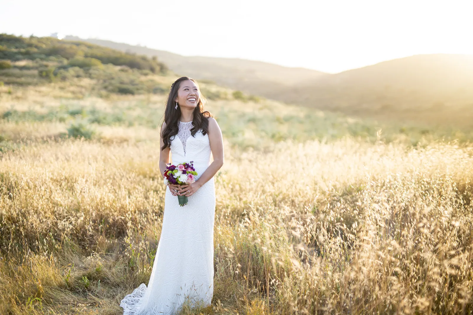 Bride walking alone through a golden meadow at sunset